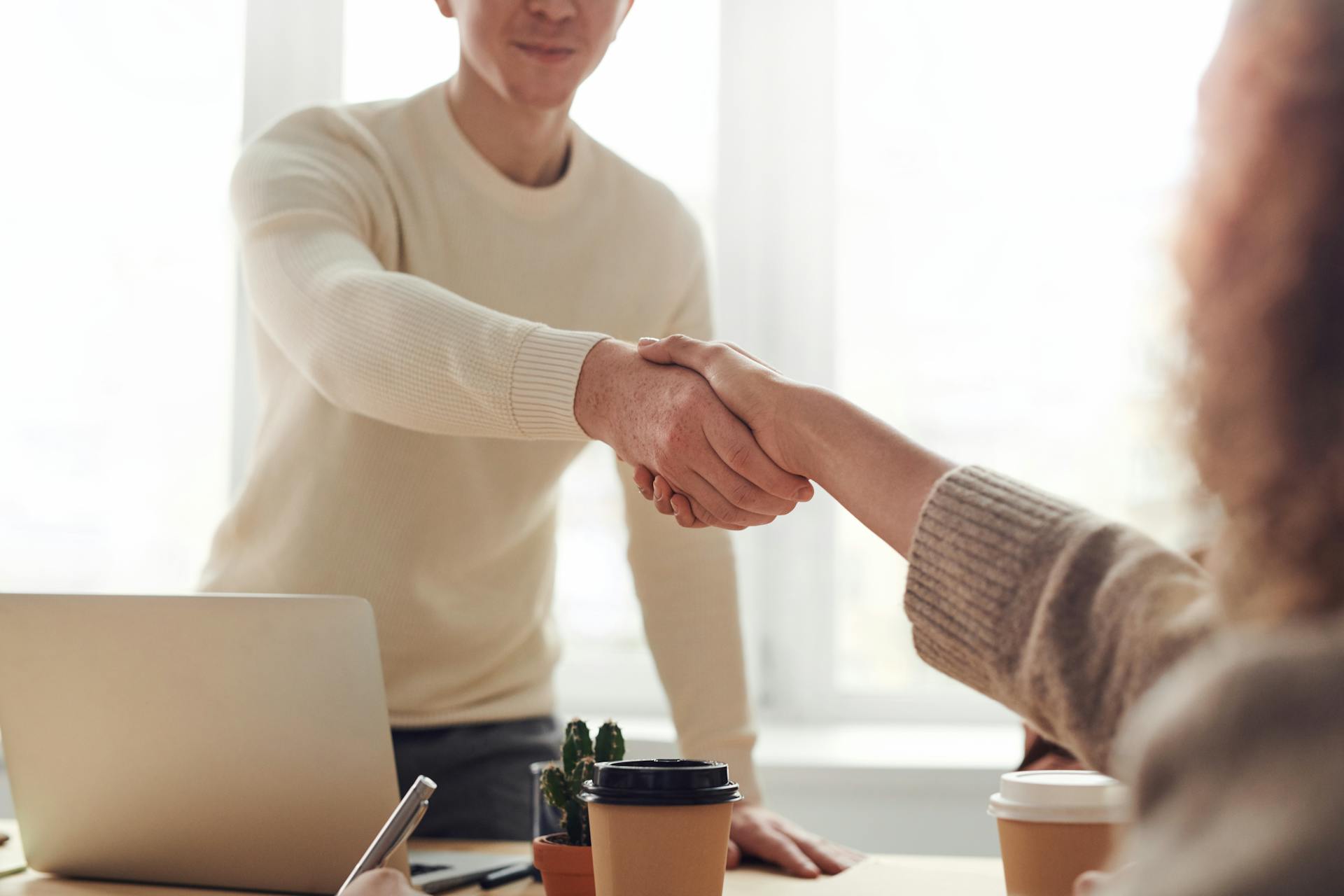 Una mujer da la mano a un hombre en una oficina | Fuente: Pexels
