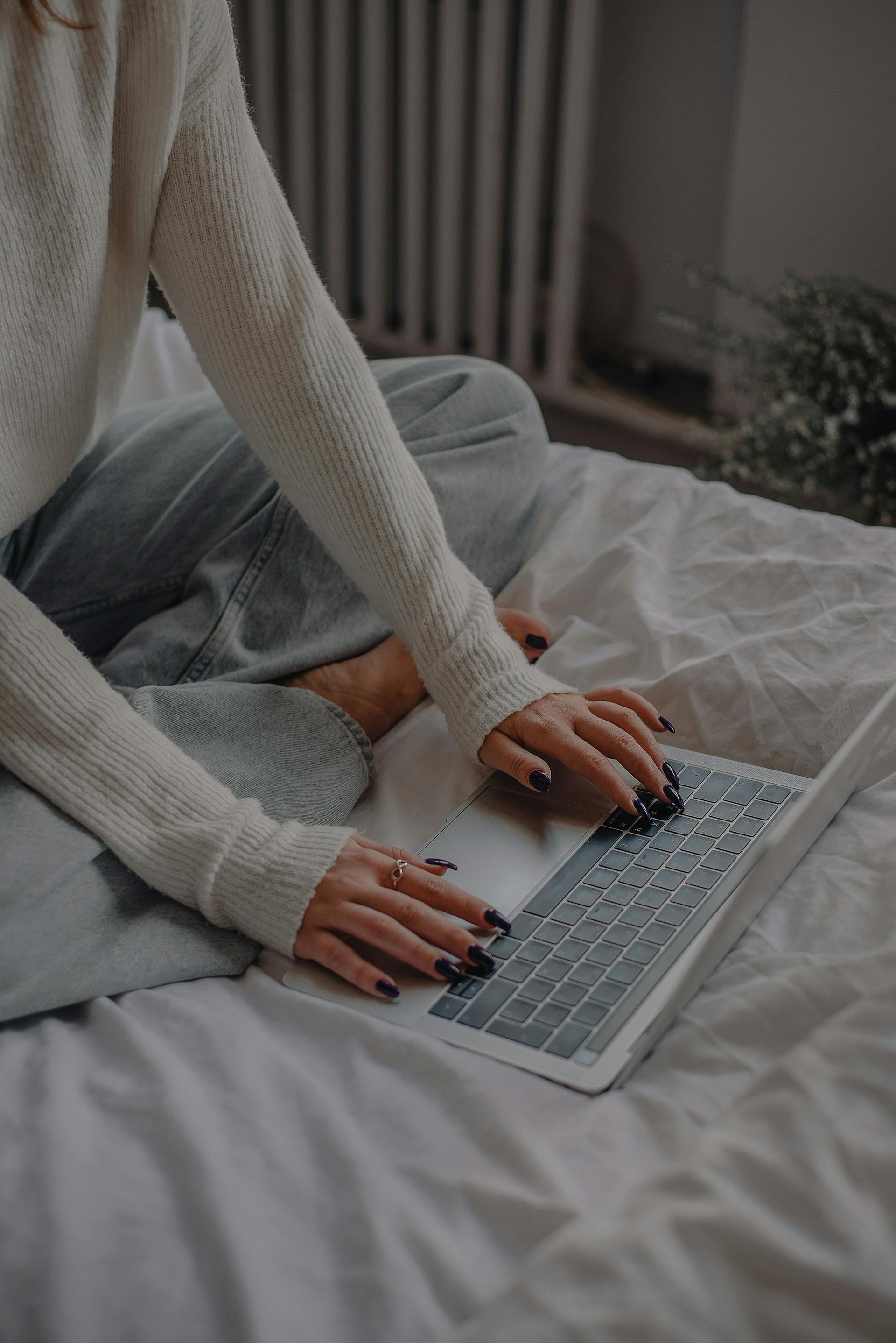 Primer plano de una mujer utilizando su portátil en la cama | Fuente: Pexels