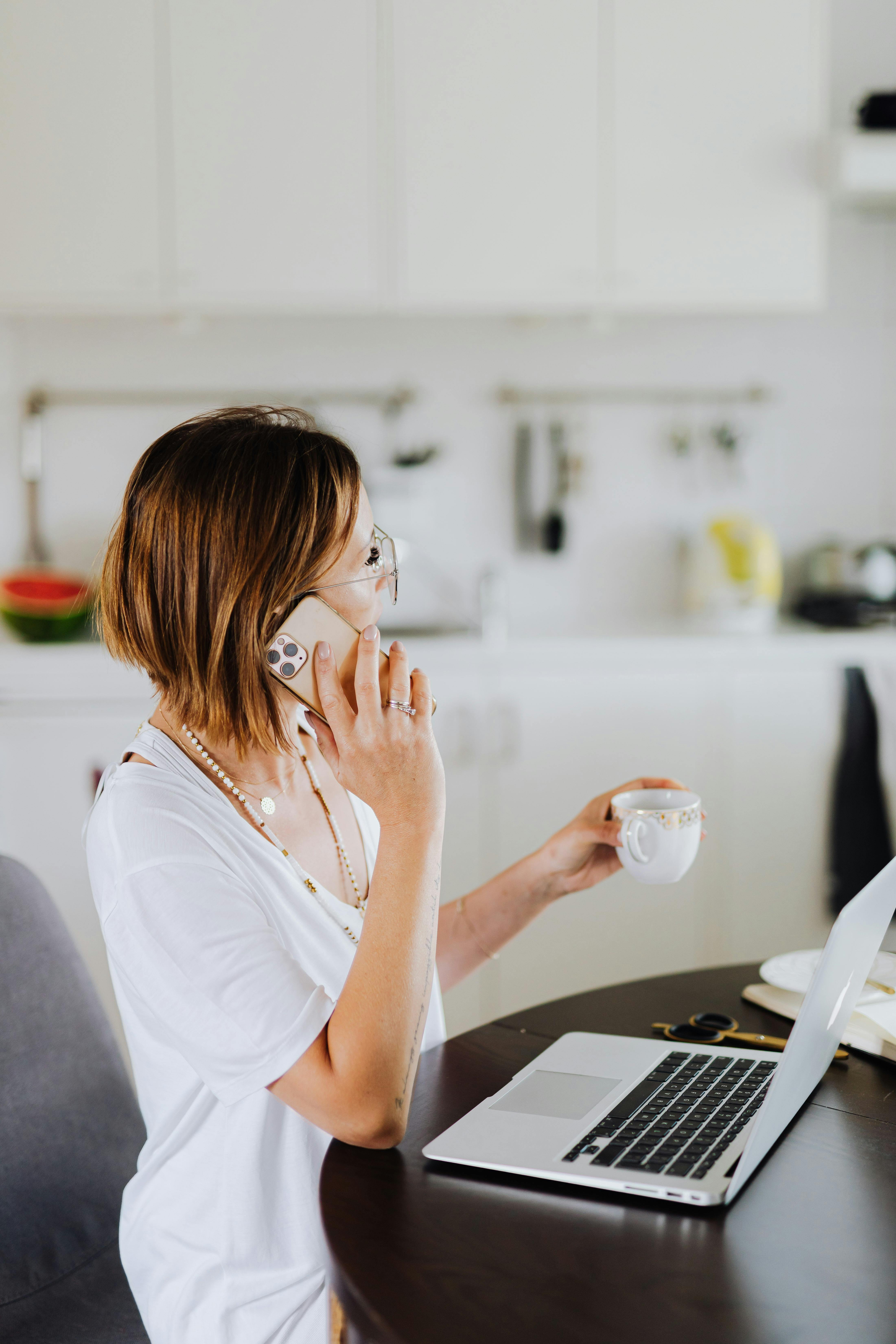 Mujer hablando por teléfono mientras sostiene una bebida| Fuente: Pexels