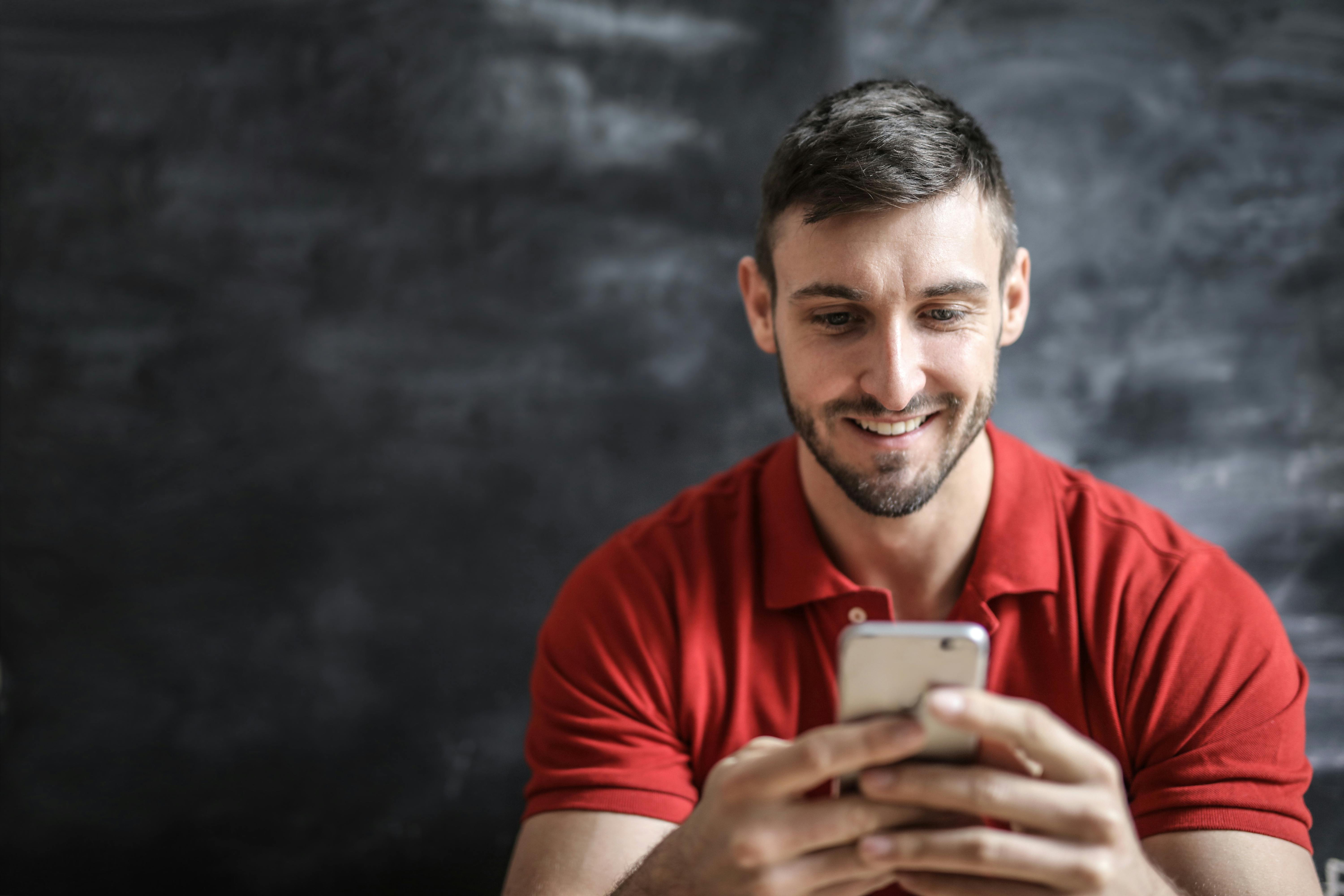 Un hombre feliz usando su teléfono | Fuente: Pexels
