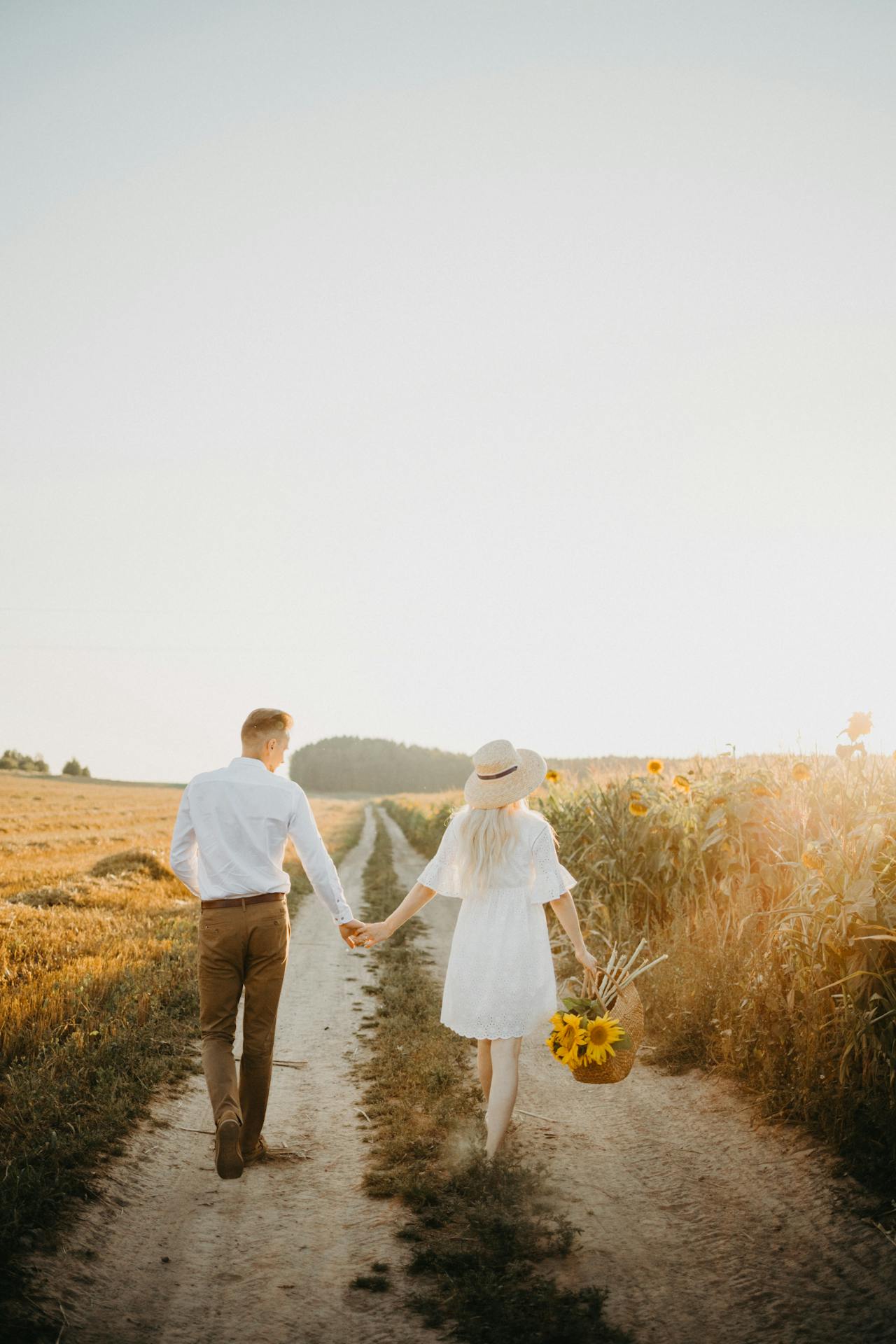 Una mujer sostiene una cesta de girasoles y camina con un hombre | Fuente: Pexels
