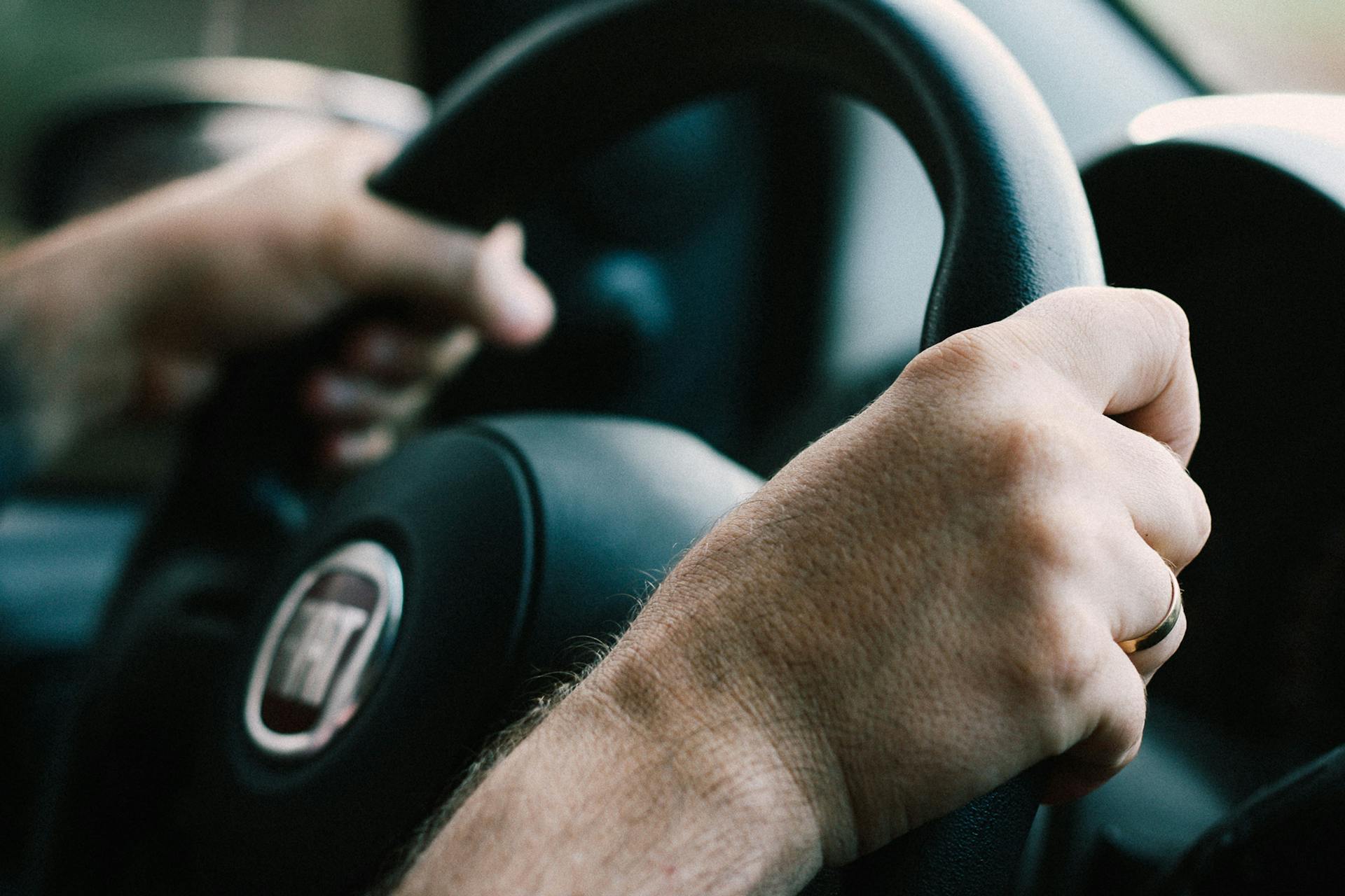 Primer plano de las manos de un hombre agarrando con fuerza el volante | Fuente: Pexels
