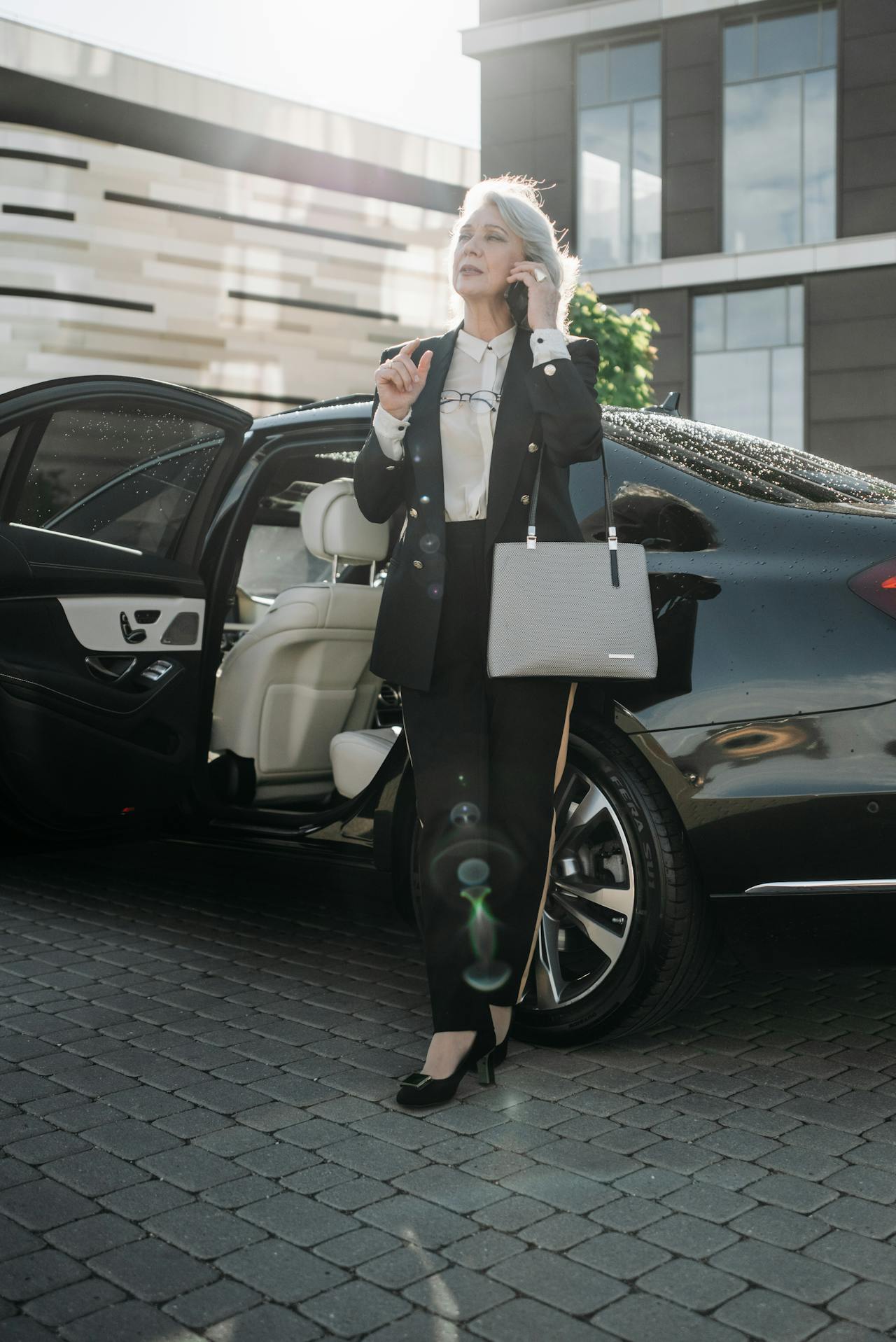 Una elegante mujer mayor junto a su automóvil y hablando por teléfono | Fuente: Pexels