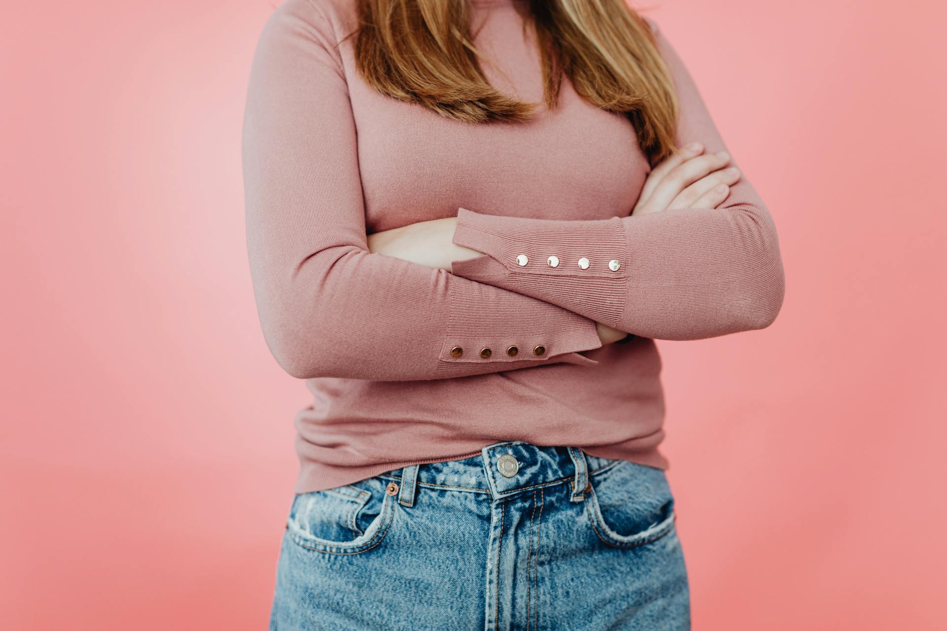 Foto recortada de una chica con un jersey rosa y vaqueros azules | Fuente: Pexels
