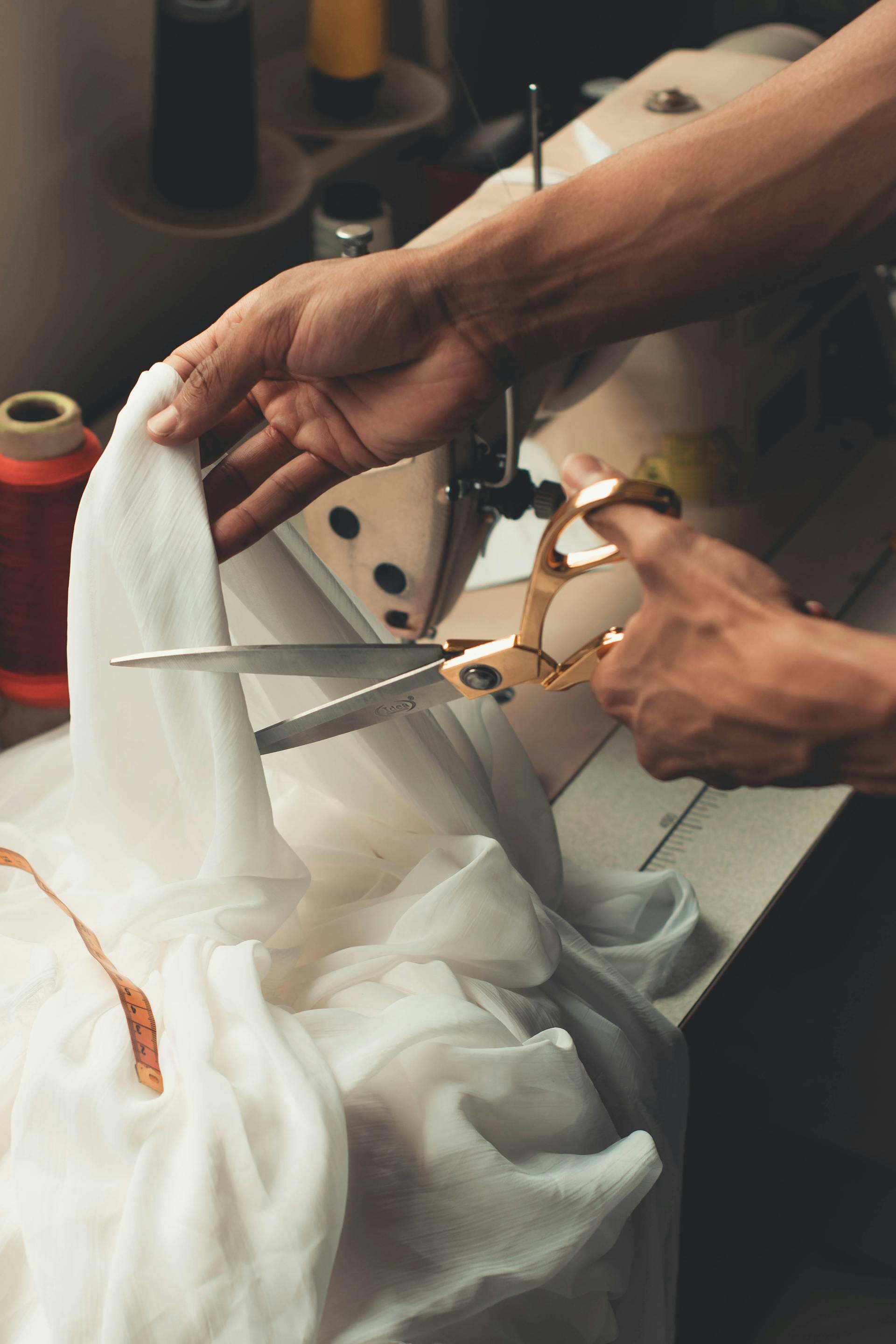 Alguien usando unas tijeras para cortar tela blanca | Fuente: Pexels