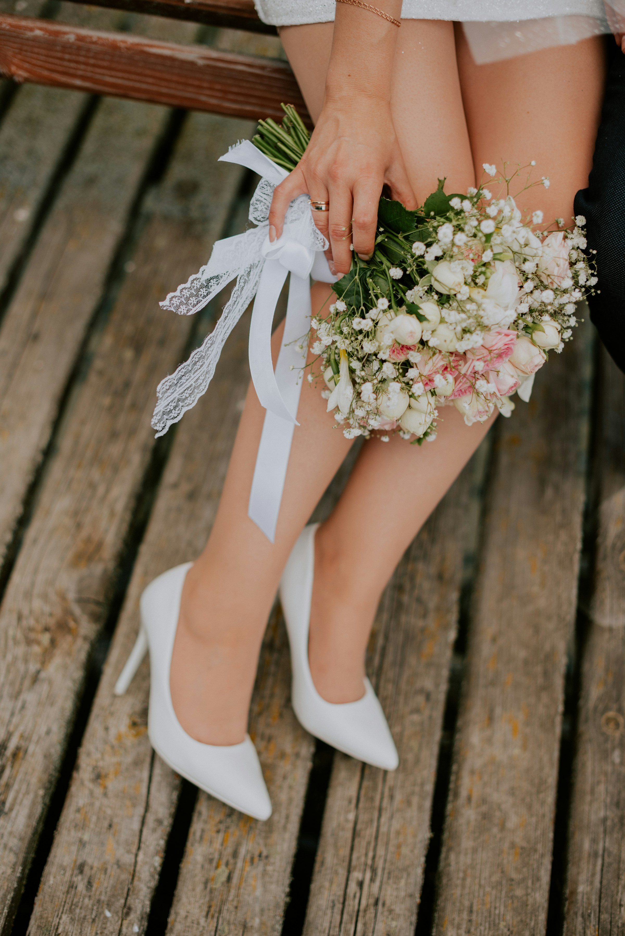 Una novia con tacones blancos sujetando flores | Fuente: Unsplash