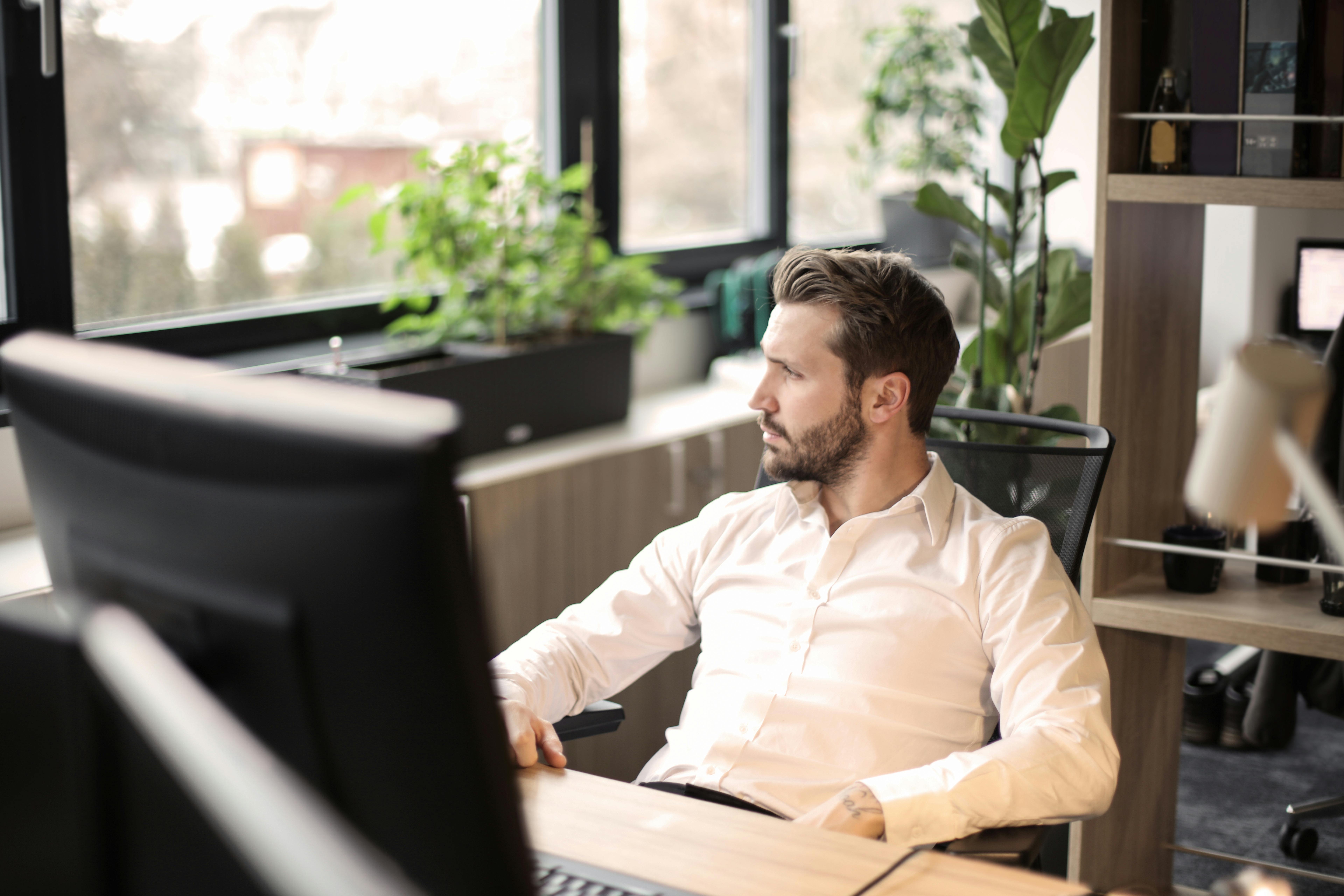 Un hombre mirando por la ventana sentado en una silla | Fuente: Pexels