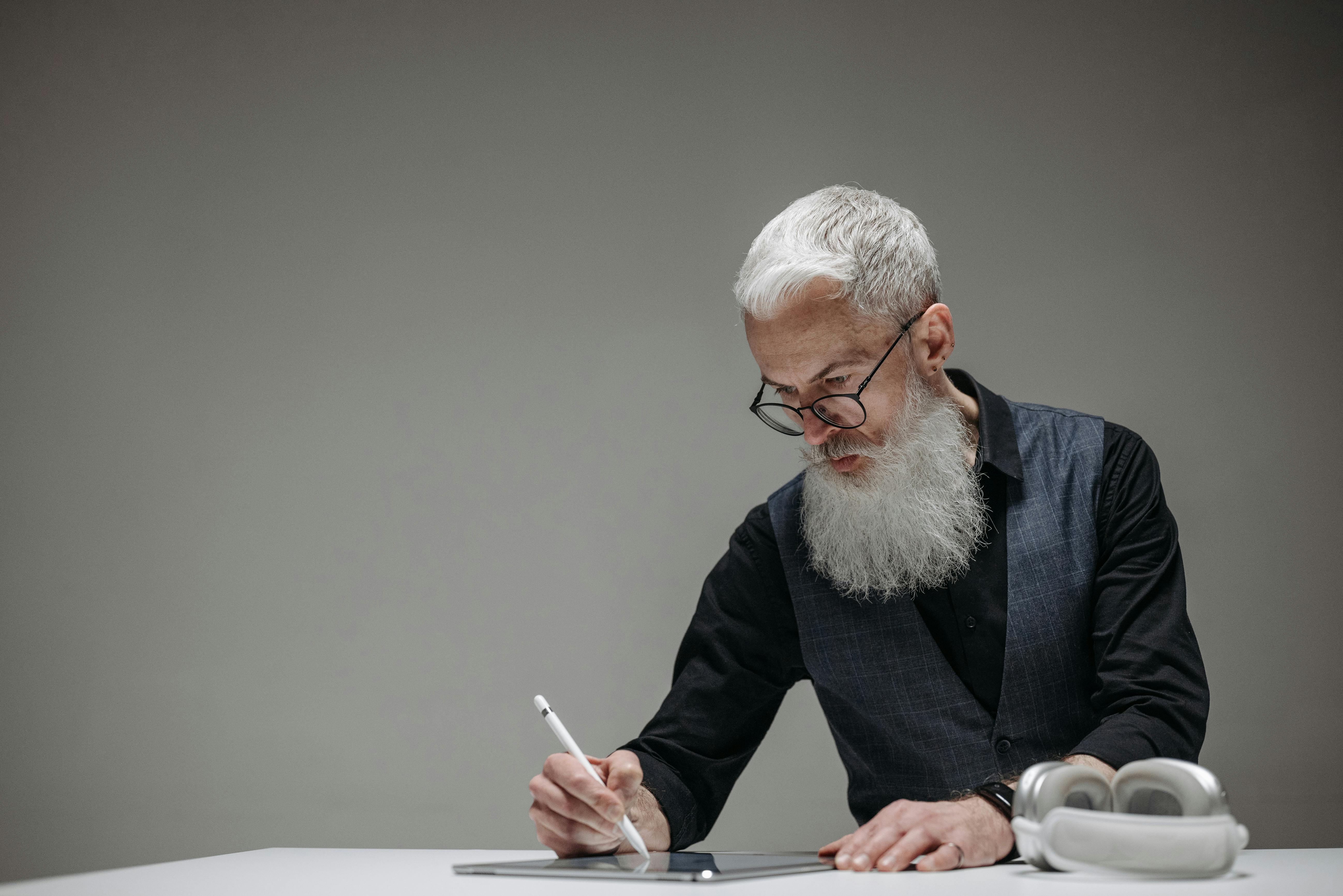 Hombre barbudo utilizando un lápiz óptico en una tableta | Fuente: Pexels