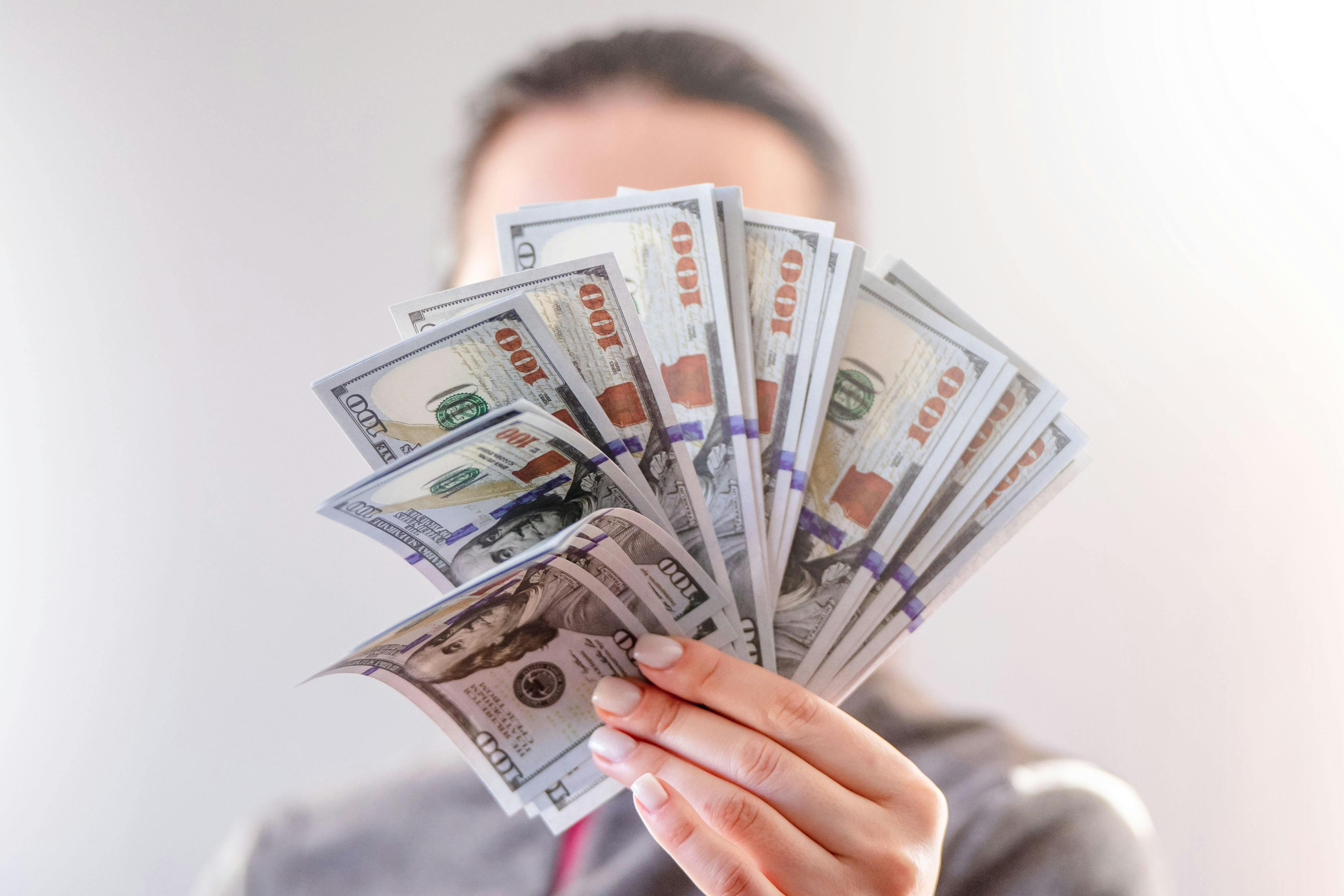 Mujer sujetando un fajo de billetes | Fuente: Pexels