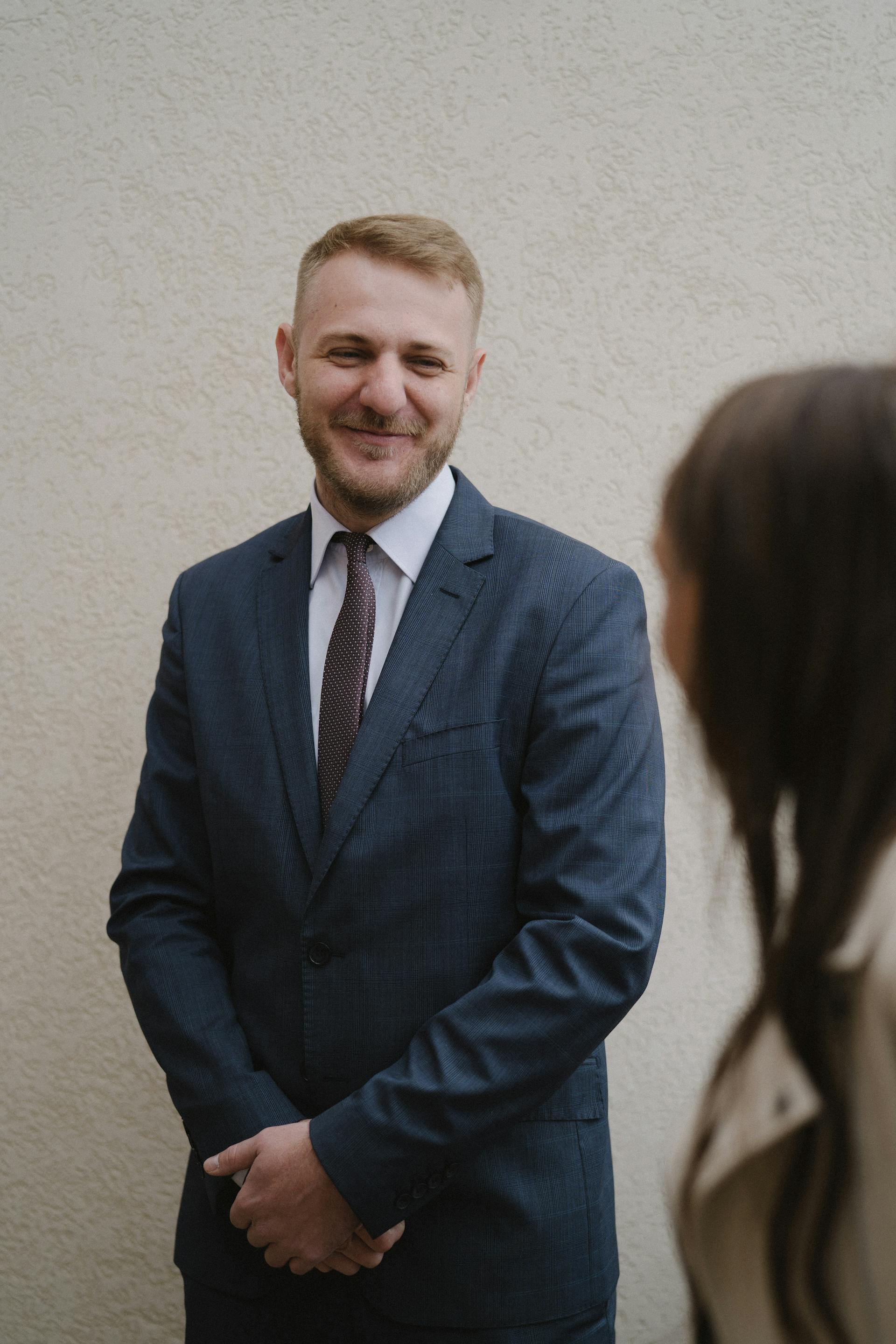 Un hombre con un traje elegante sonriendo a una mujer | Fuente: Pexels