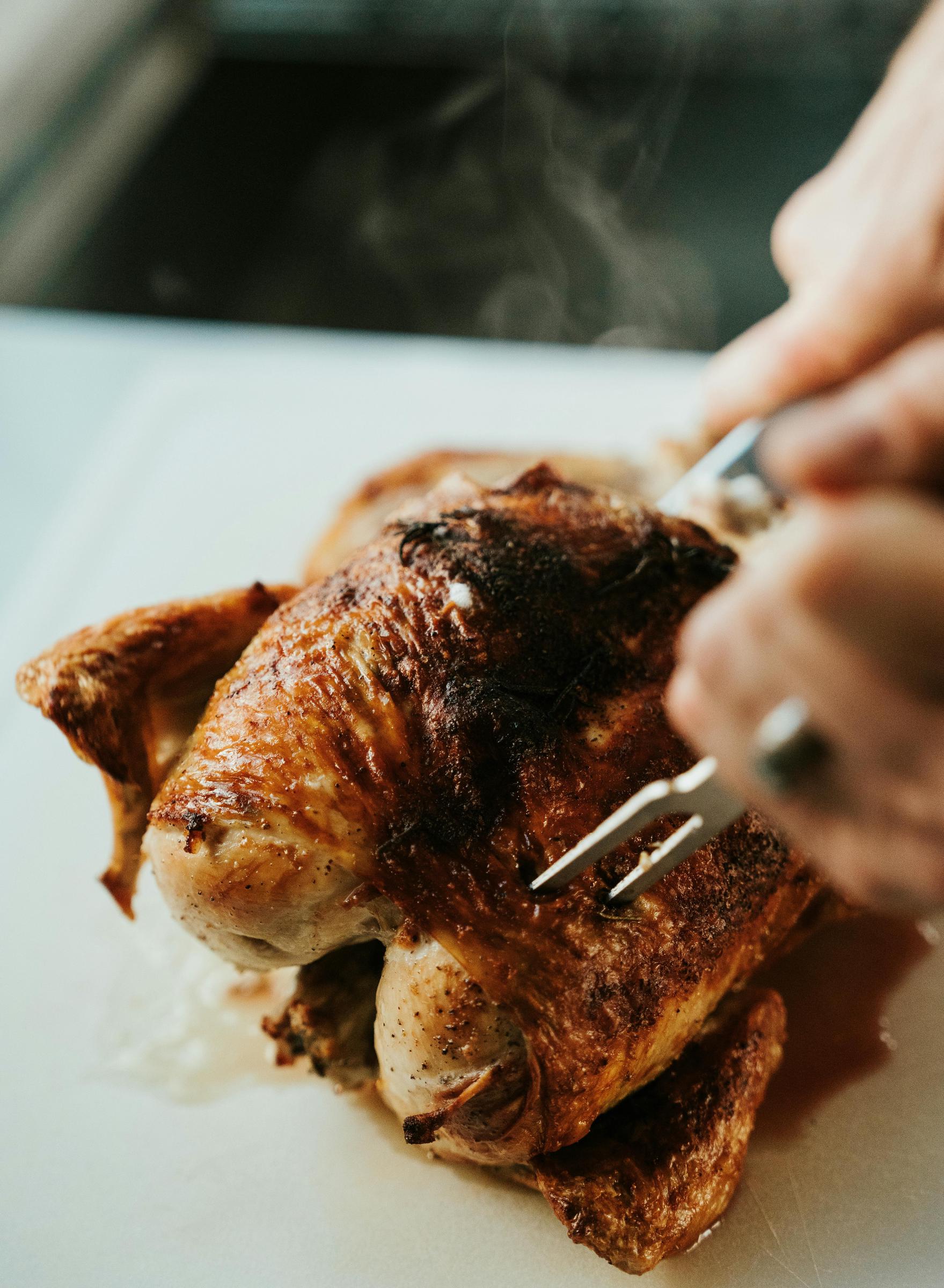 Un trozo de pollo asado siendo cortado | Fuente: Pexels