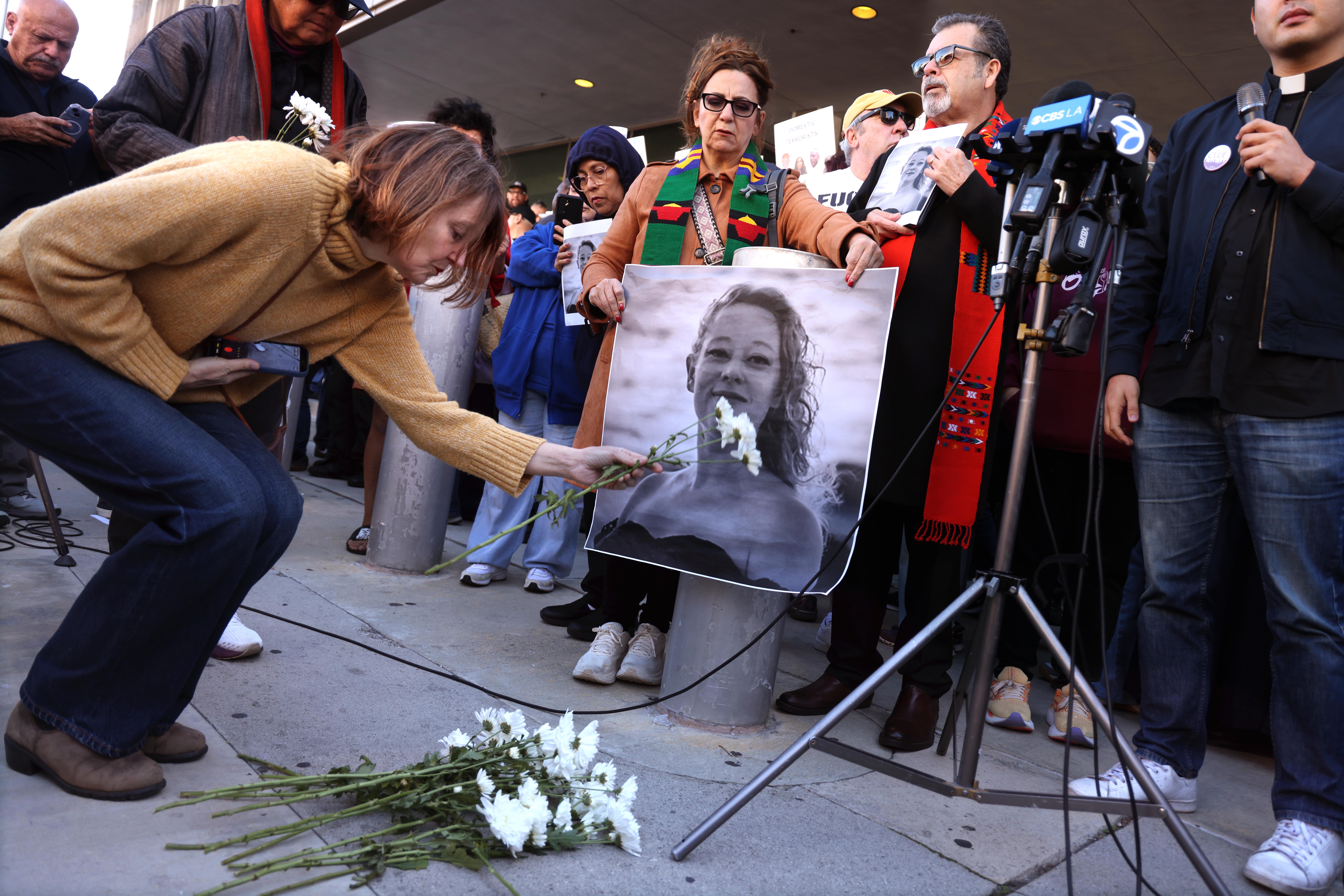 Una mujer sostiene una foto de Renee Nicole Good y observa cómo los manifestantes dejan flores en su memoria un día después de su tiroteo en Minneapolis, en el centro de Los Ángeles, el 8 de enero de 2026. | Fuente: Getty Images
