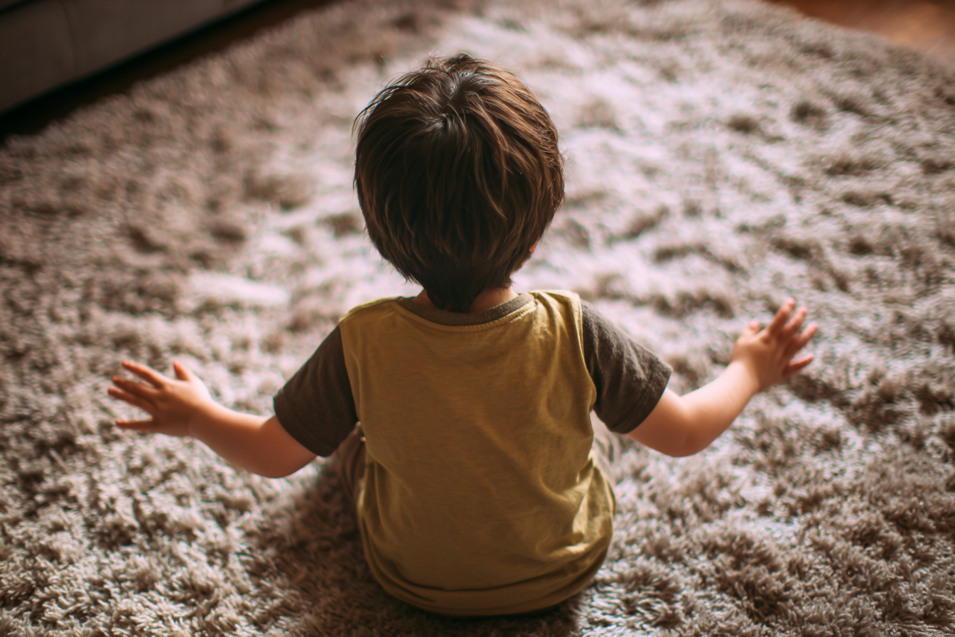 Un niño sentado en una alfombra agitando alegremente las manos | Fuente: Midjourney