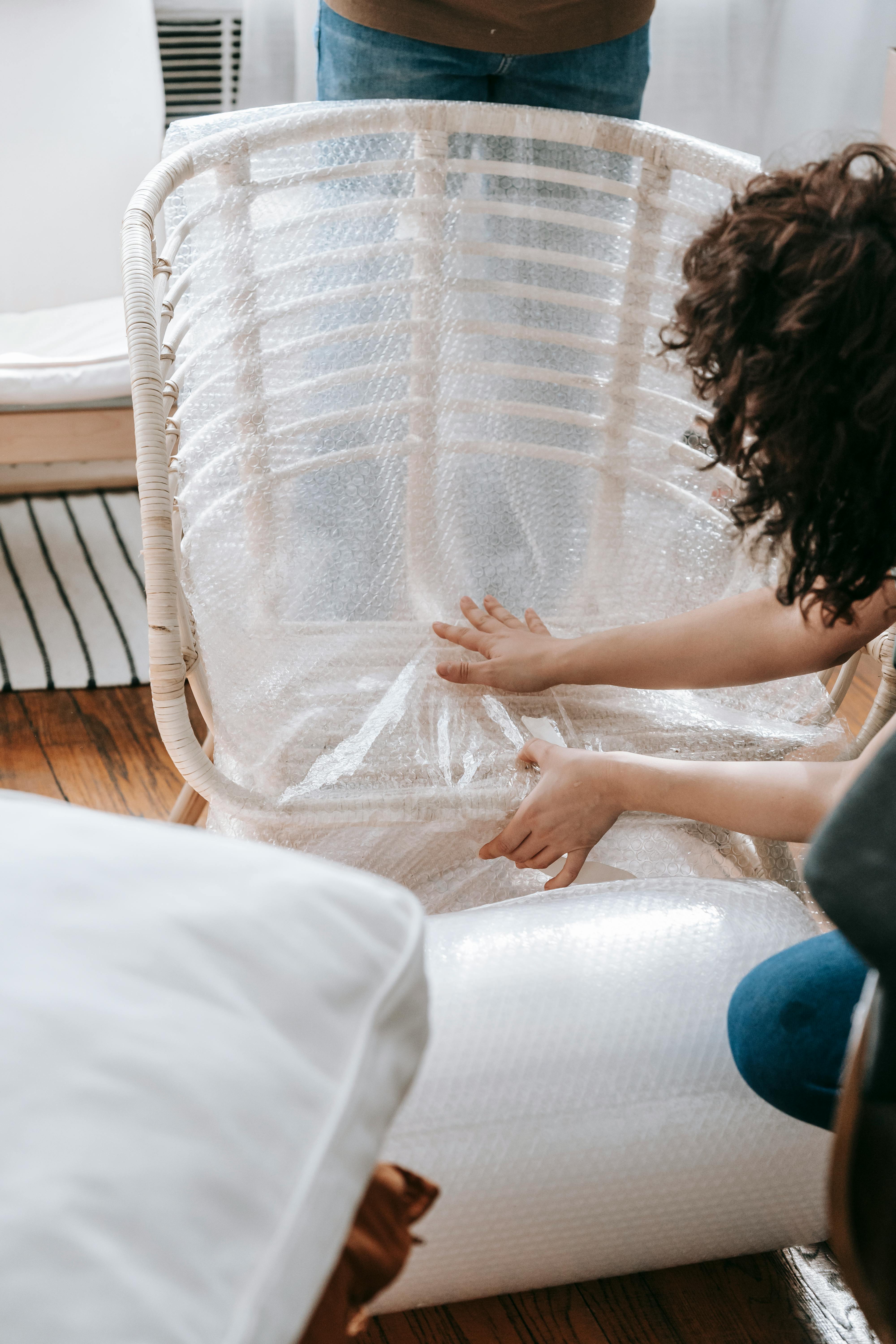Una mujer envuelve una silla en plástico de burbujas | Fuente: Pexels