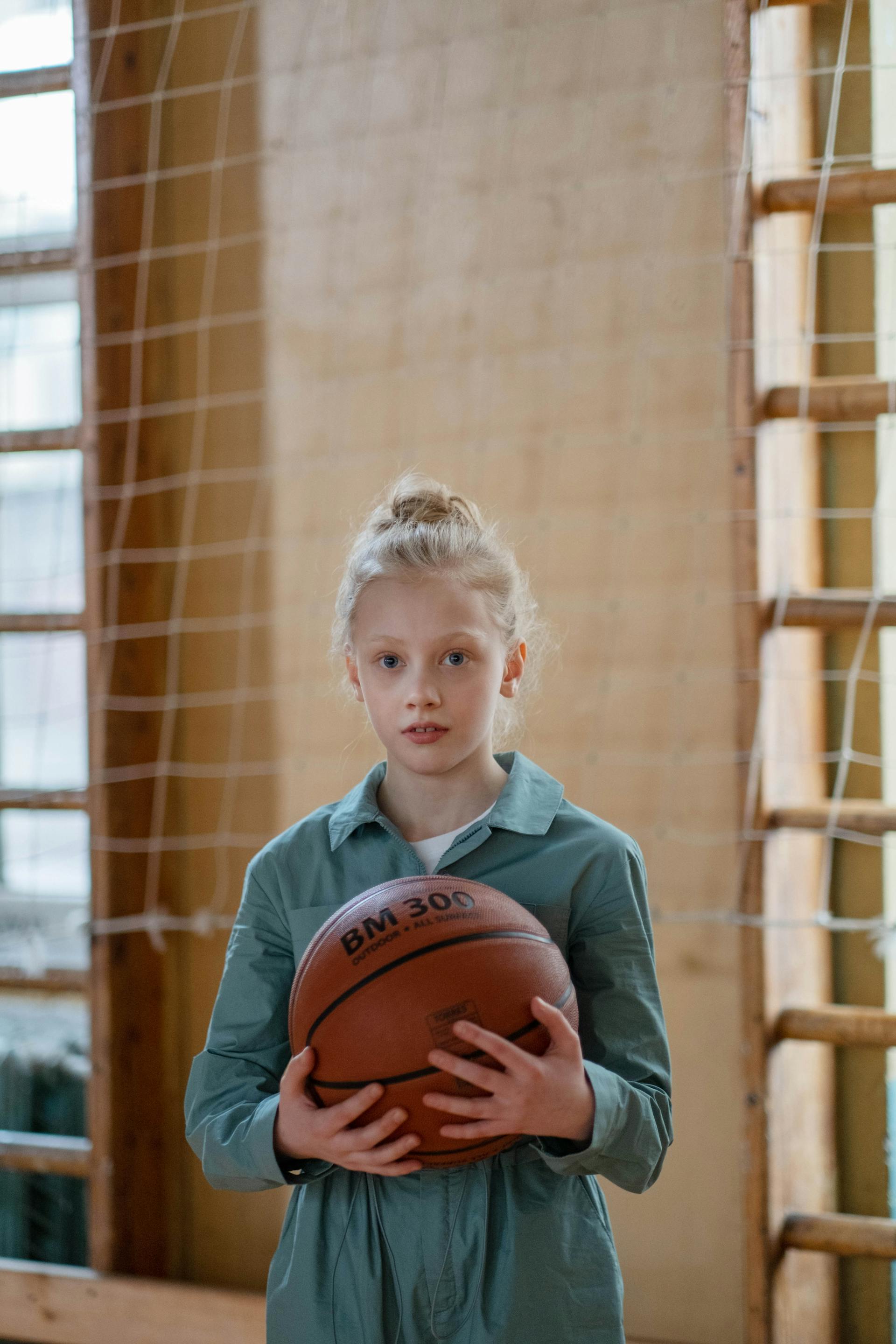 Una adolescente de aspecto nervioso sujetando una pelota de baloncesto | Fuente: Pexels