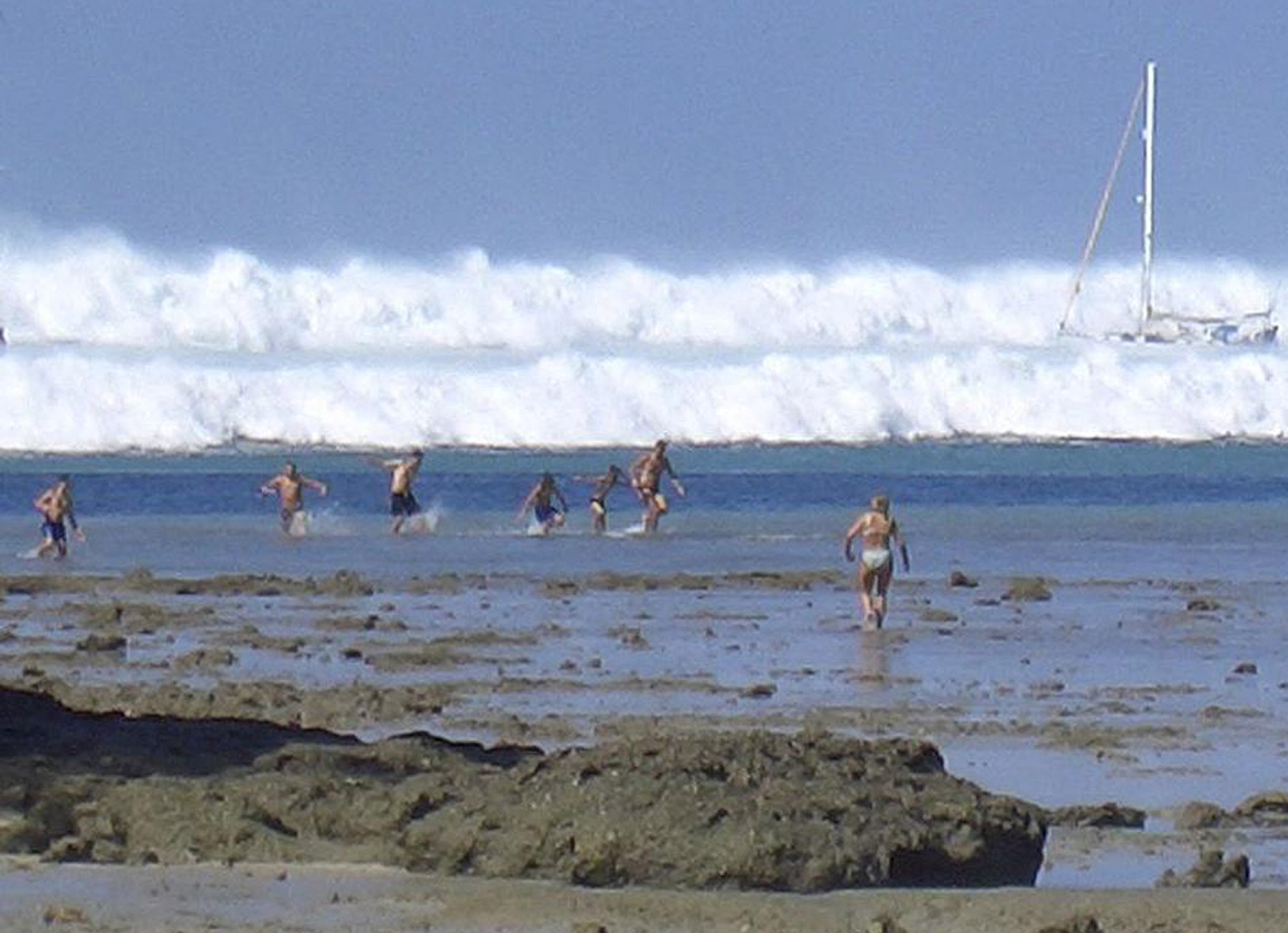 Turistas extranjeros en la arena, después de que el agua retrocediera, reaccionan cuando el primero de seis tsunamis comienza a avanzar hacia la playa Hat Rai Lay, cerca de Krabi, en el sur de Tailandia, el 26 de diciembre de 2004. | Fuente: Getty Images