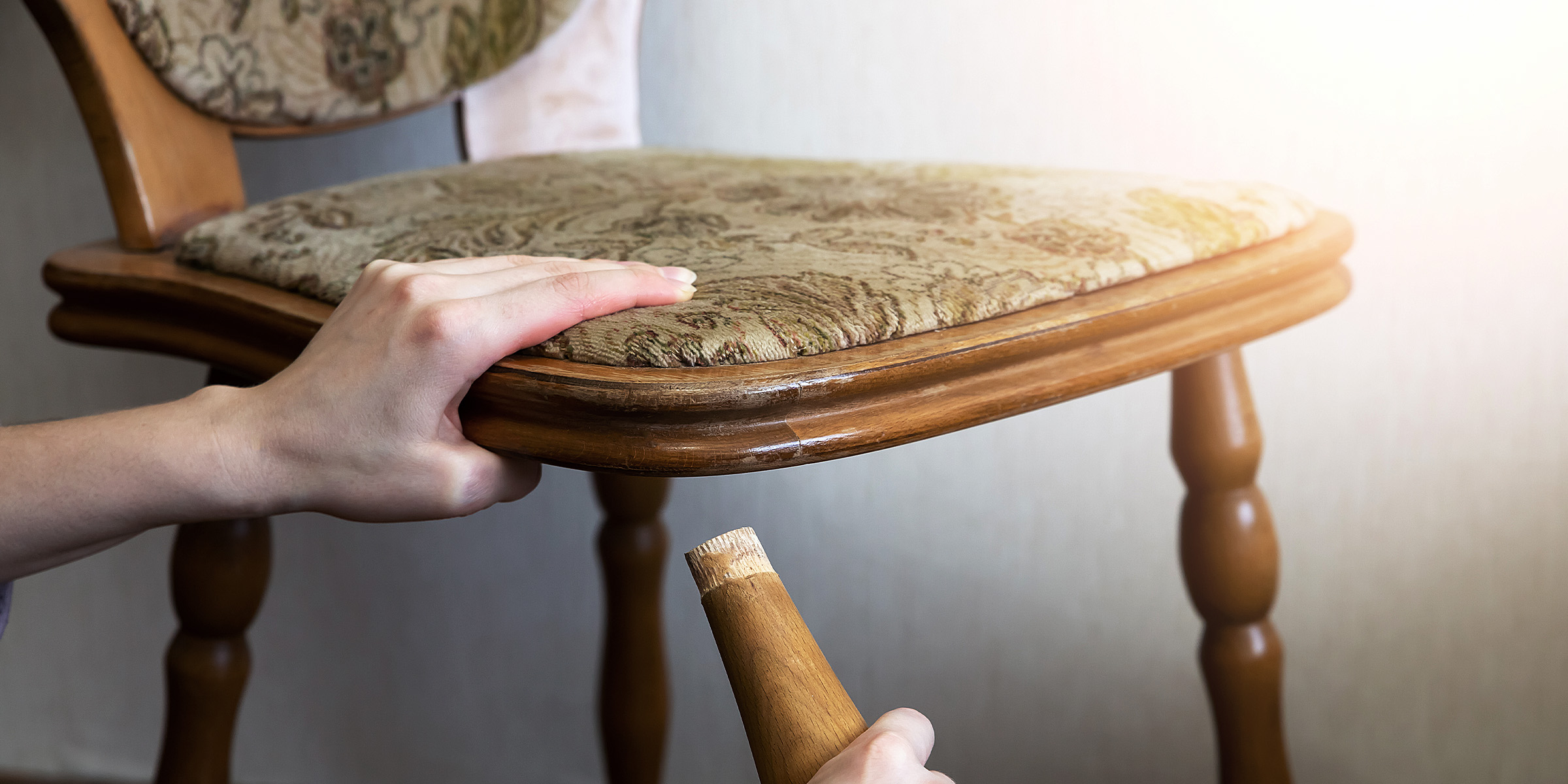 Una mujer sujetando la pata de una silla rota | Fuente: Shutterstock