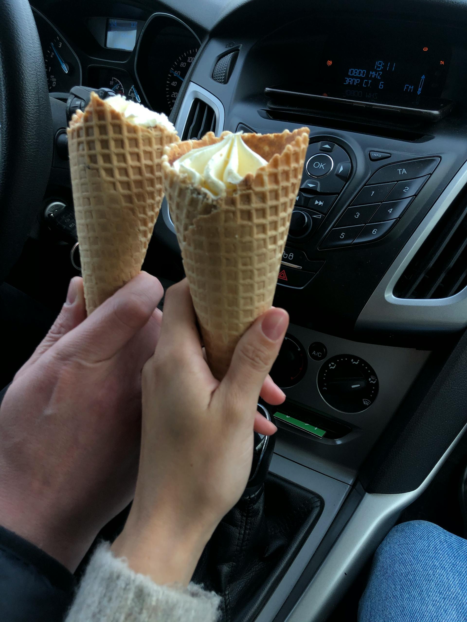 Una pareja sosteniendo cucuruchos de helado en un Automóvil | Fuente: Pexels