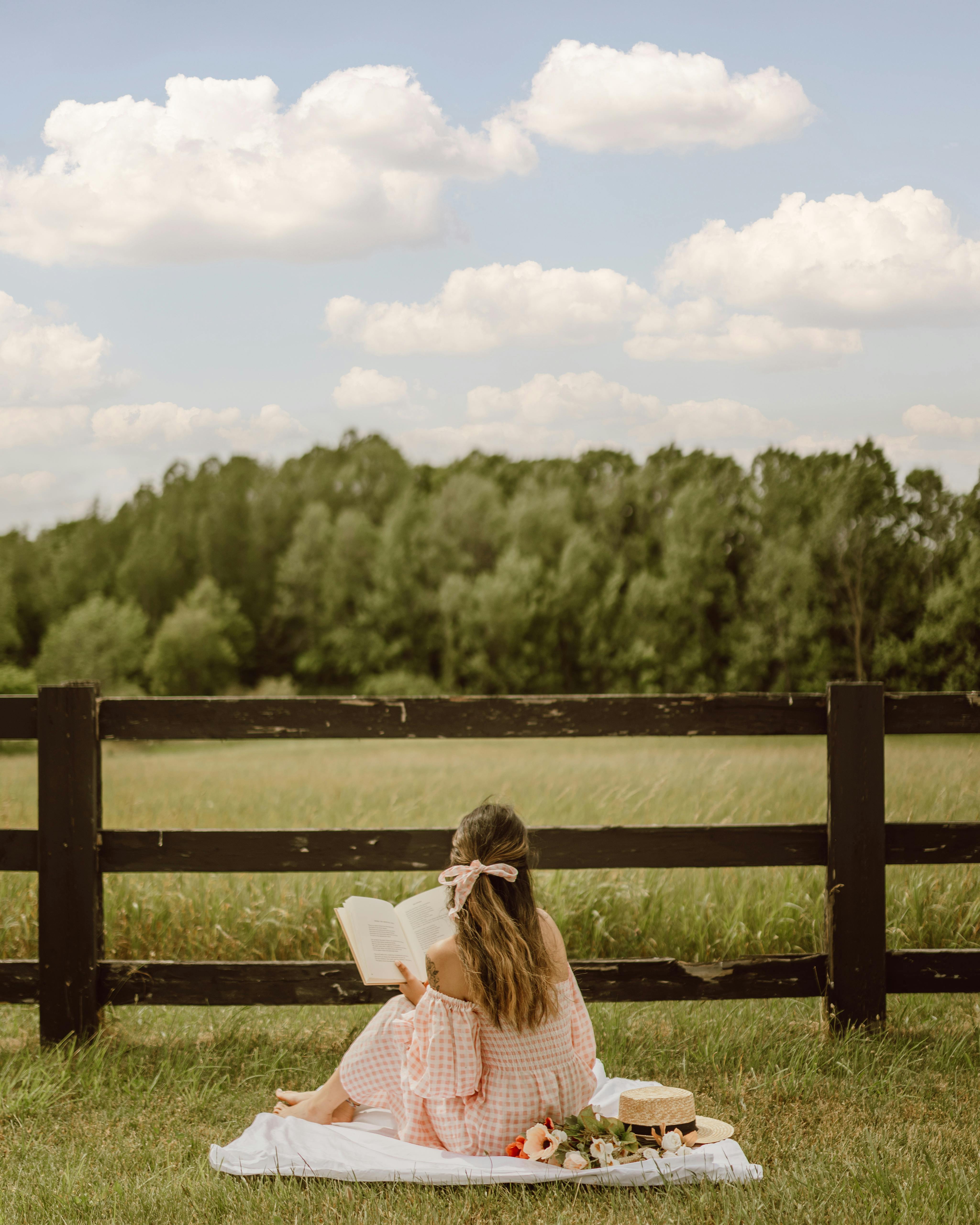 Mujer disfrutando de un picnic mientras lee un libro | Fuente: Pexels