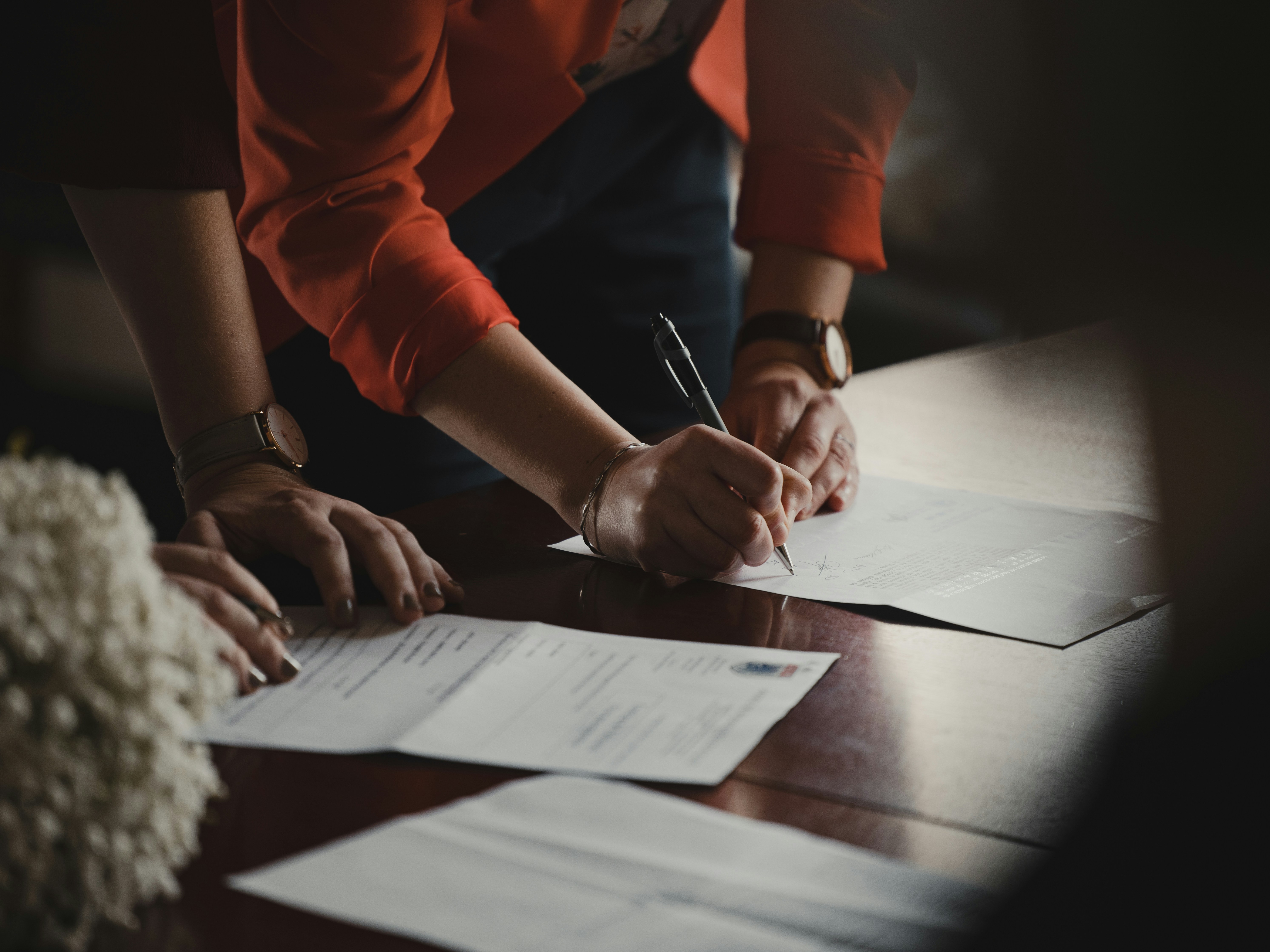 Gente firmando documentos sobre la mesa | Fuente: Unsplash