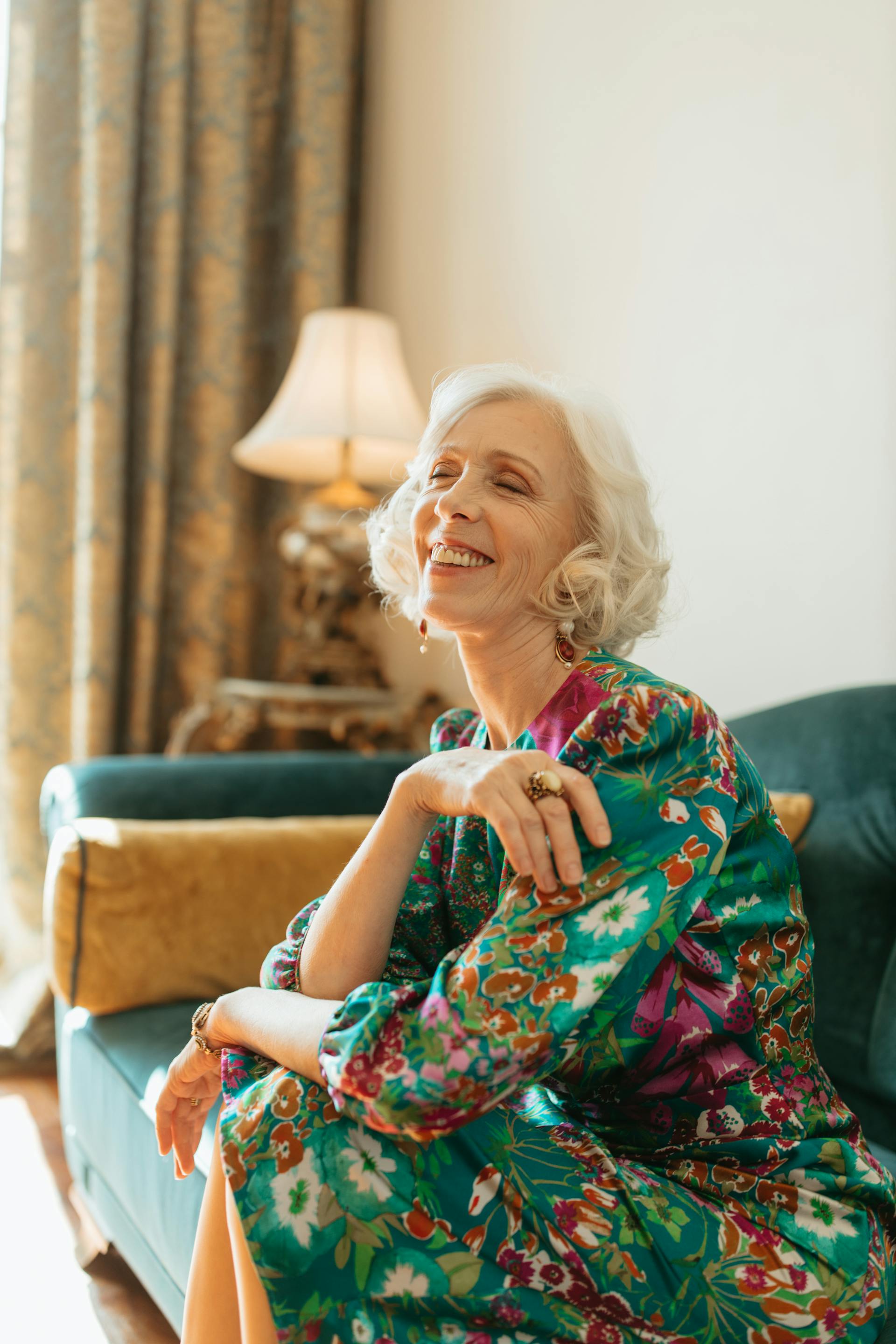 Una anciana sentada en el sofá y riendo | Fuente: Pexels