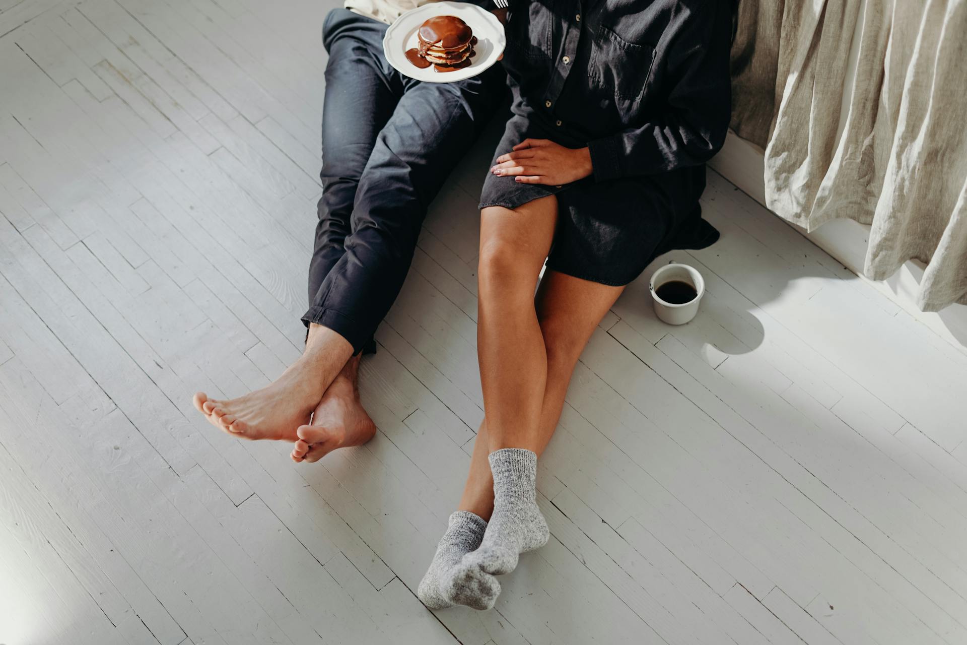Primer plano de una pareja desayunando en el suelo | Fuente: Pexels