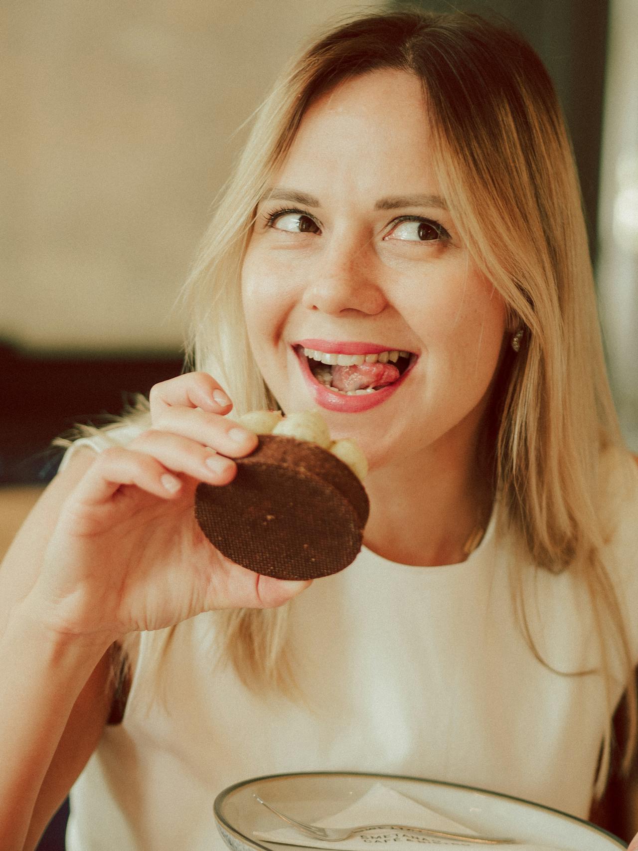 Una mujer feliz comiendo una magdalena | Fuente: Pexels