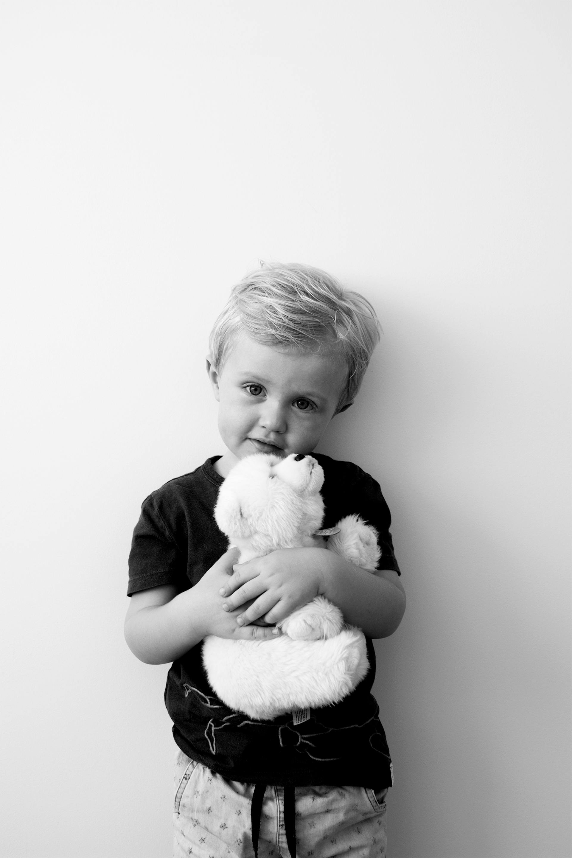 Foto en escala de grises de un niño sujetando un oso de peluche | Fuente: Pexels