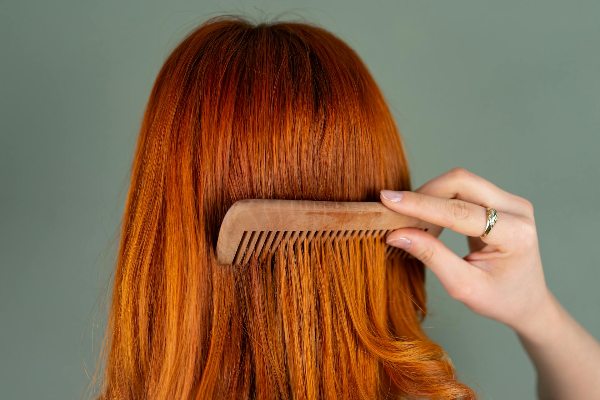 Una mujer peinándose el pelo castaño | Fuente: Pexels