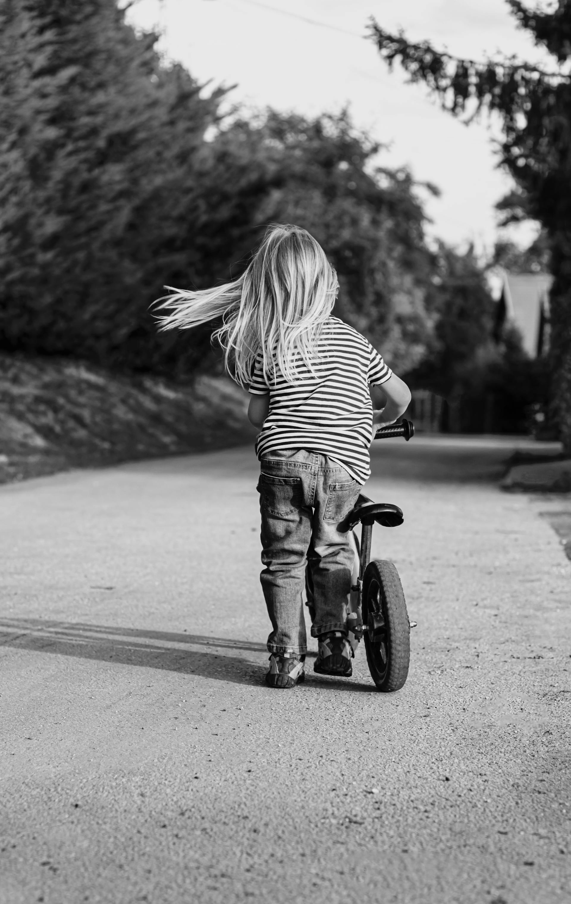 Toma en escala de grises de una niña montando en bicicleta | Fuente: Pexels