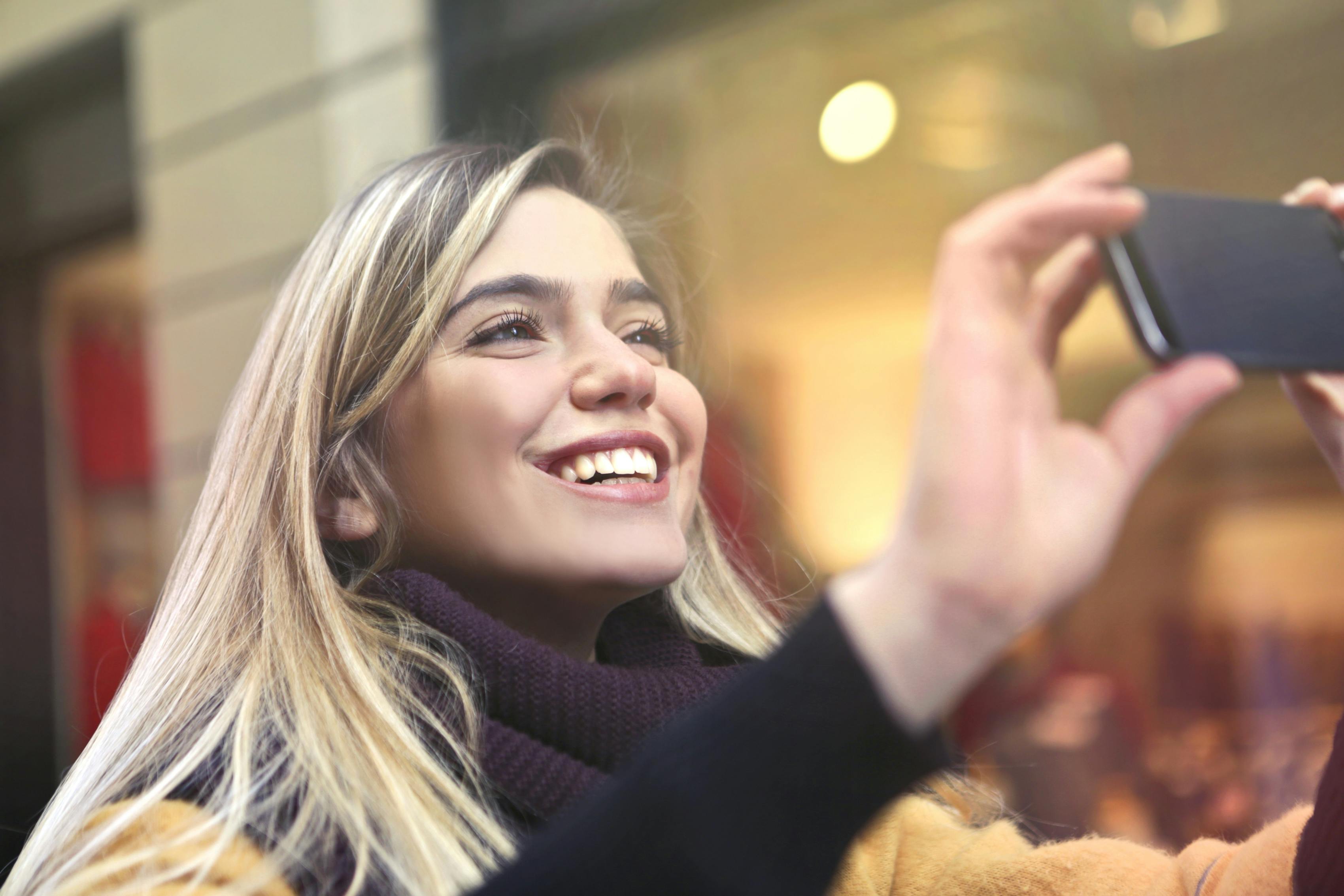 Una mujer feliz haciendo fotos | Fuente: Pexels
