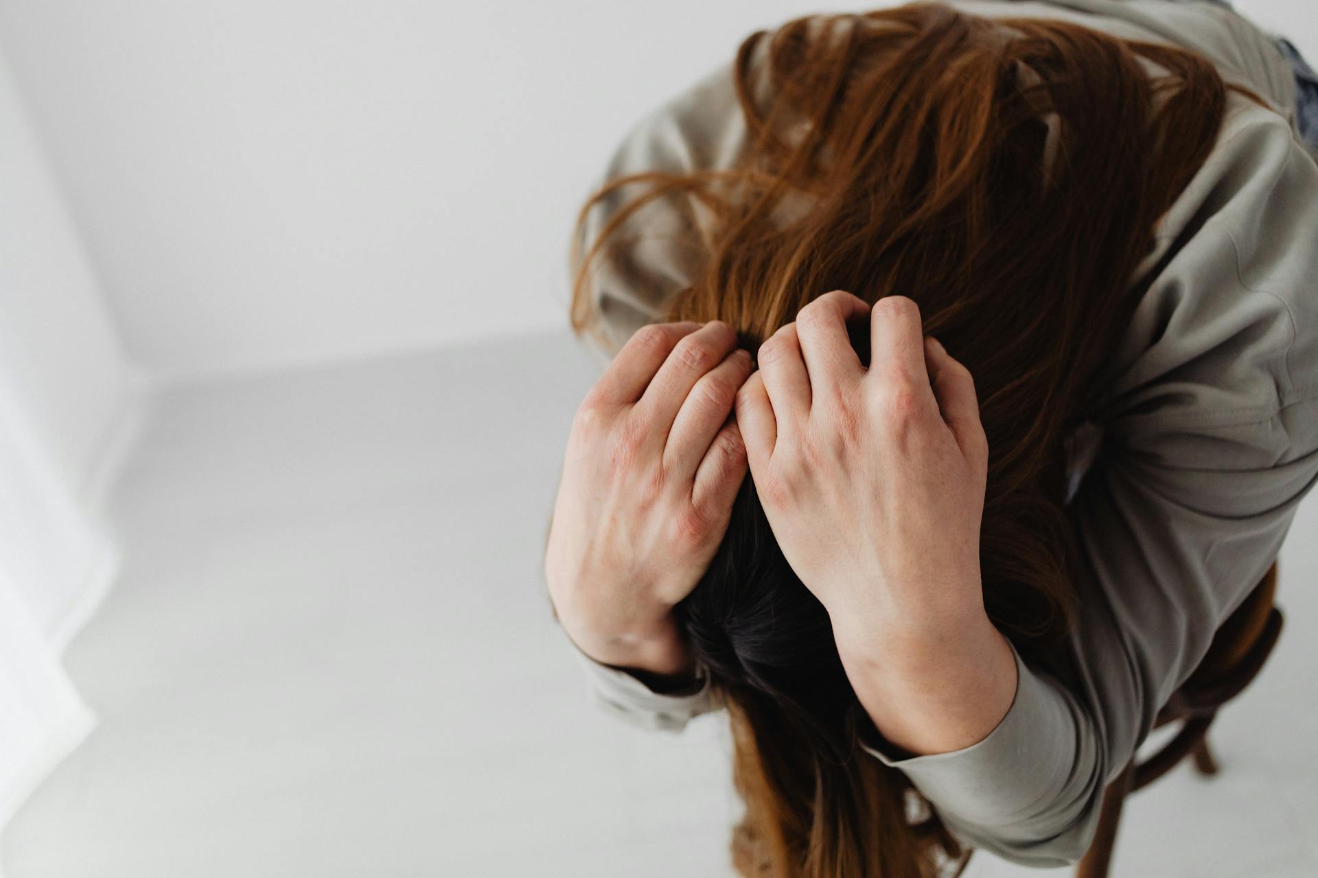 Una mujer sentada con la cabeza entre las manos | Fuente: Pexels