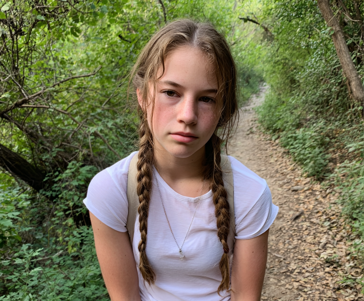 Una adolescente estresada con una camiseta blanca en una excursión | Fuente: Midjourney