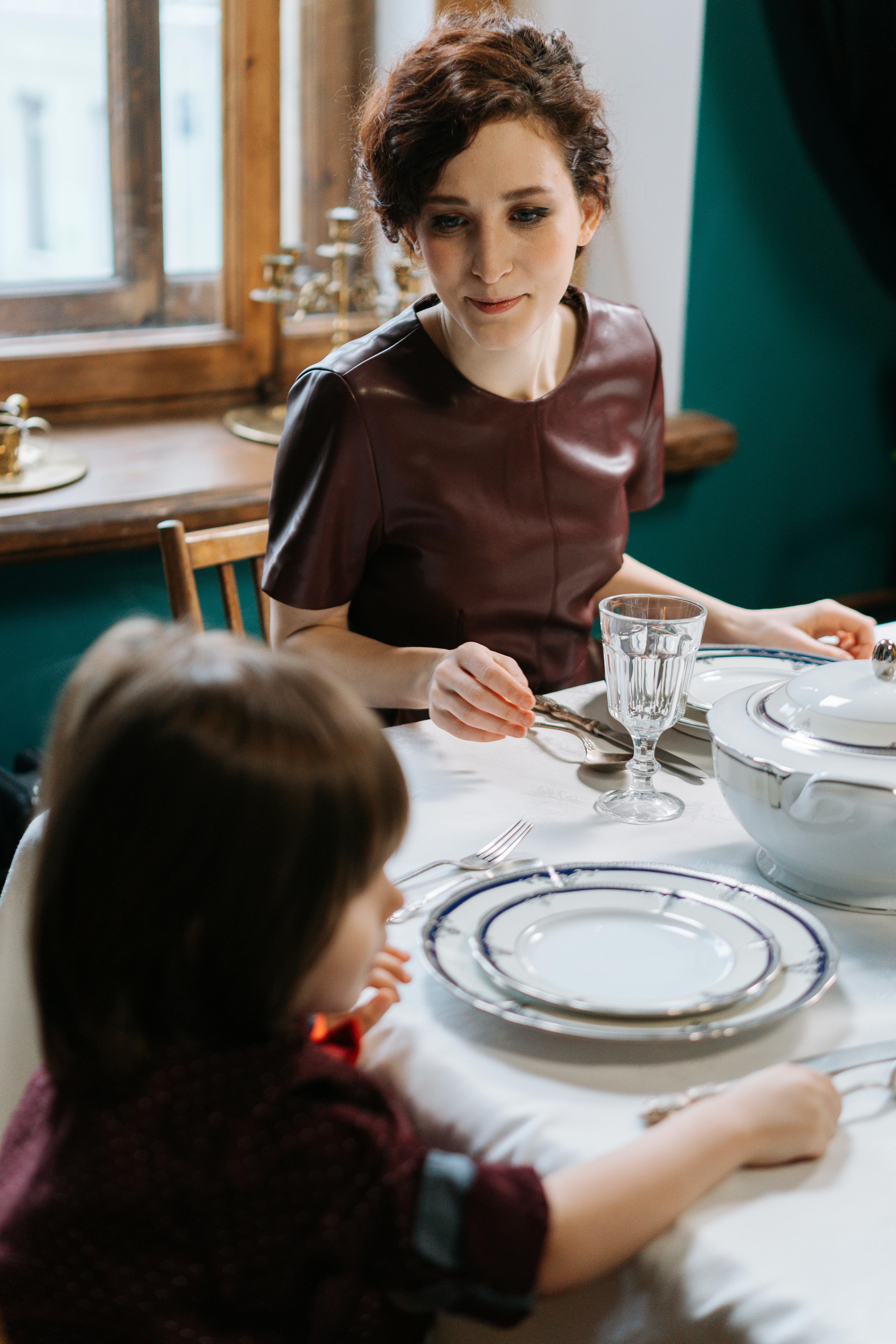 Niñera mirando a un niño sentado a su lado | Fuente: Pexels