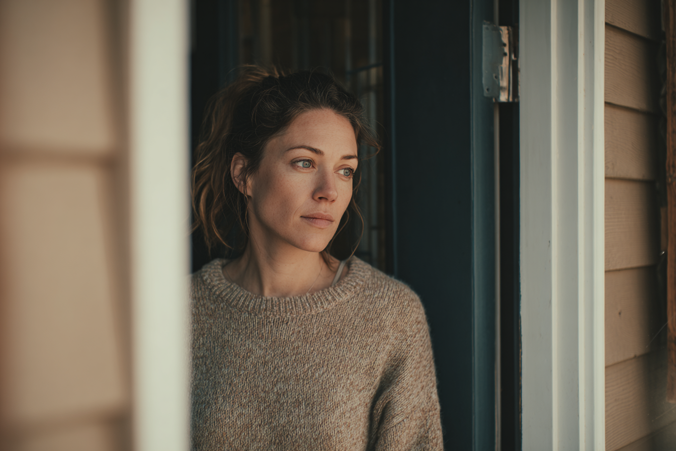 Una mujer en la puerta de su casa | Fuente: Midjourney