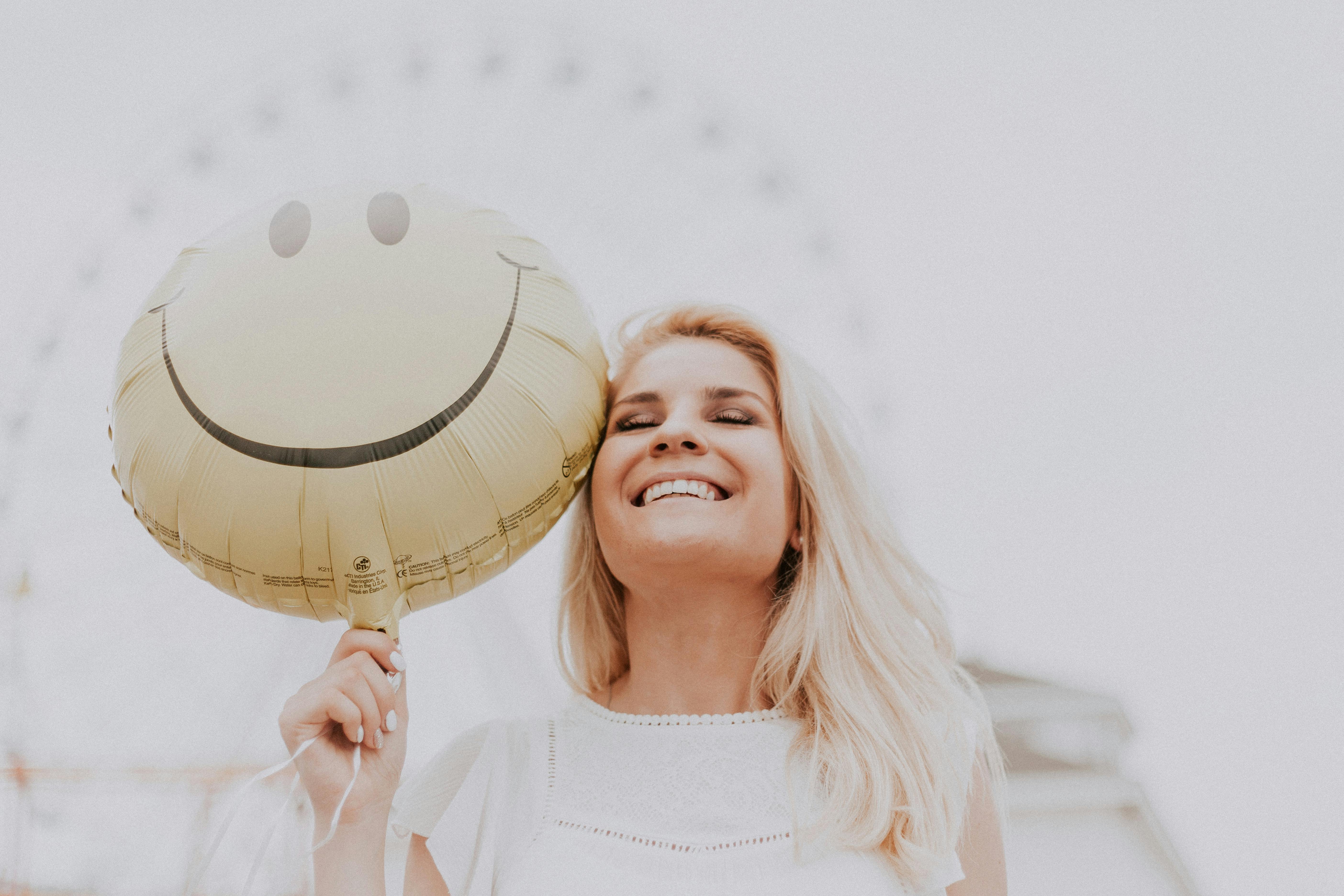 Una mujer sonriente sujetando un globo | Fuente: Pexels