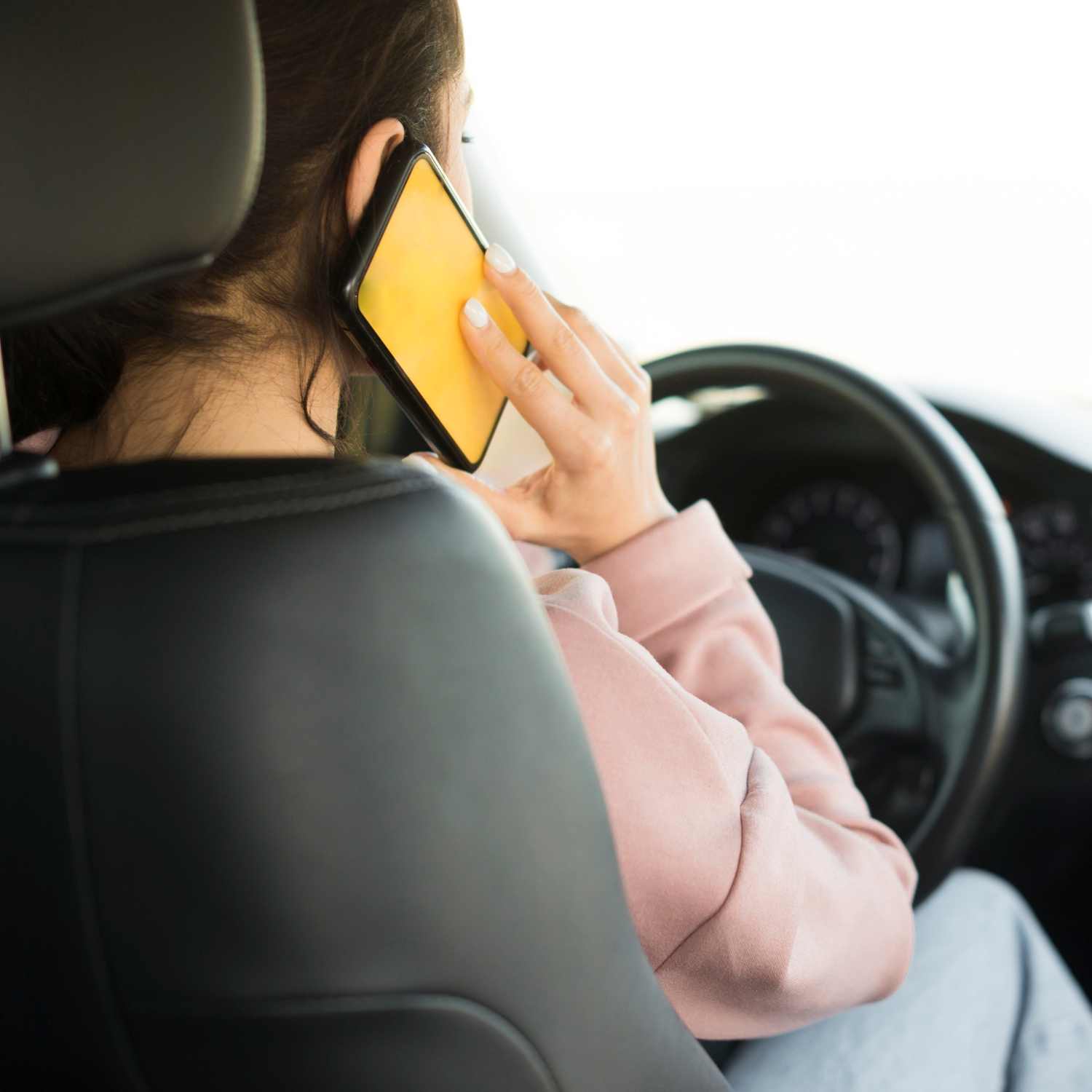 Una mujer hablando por teléfono sentada al volante | Fuente: Freepik