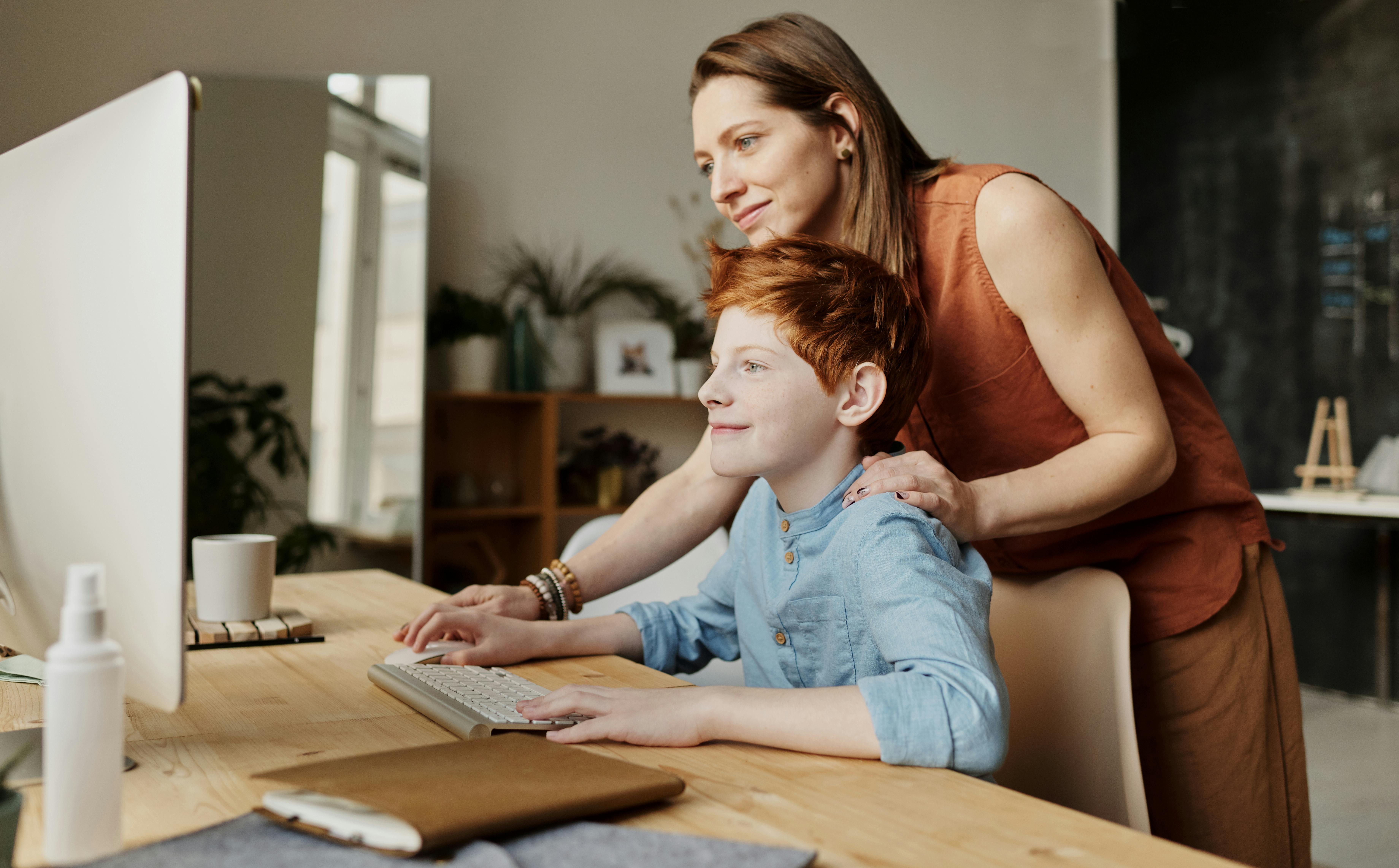 Una mujer con un niño trabajando en un ordenador | Fuente: Pexels