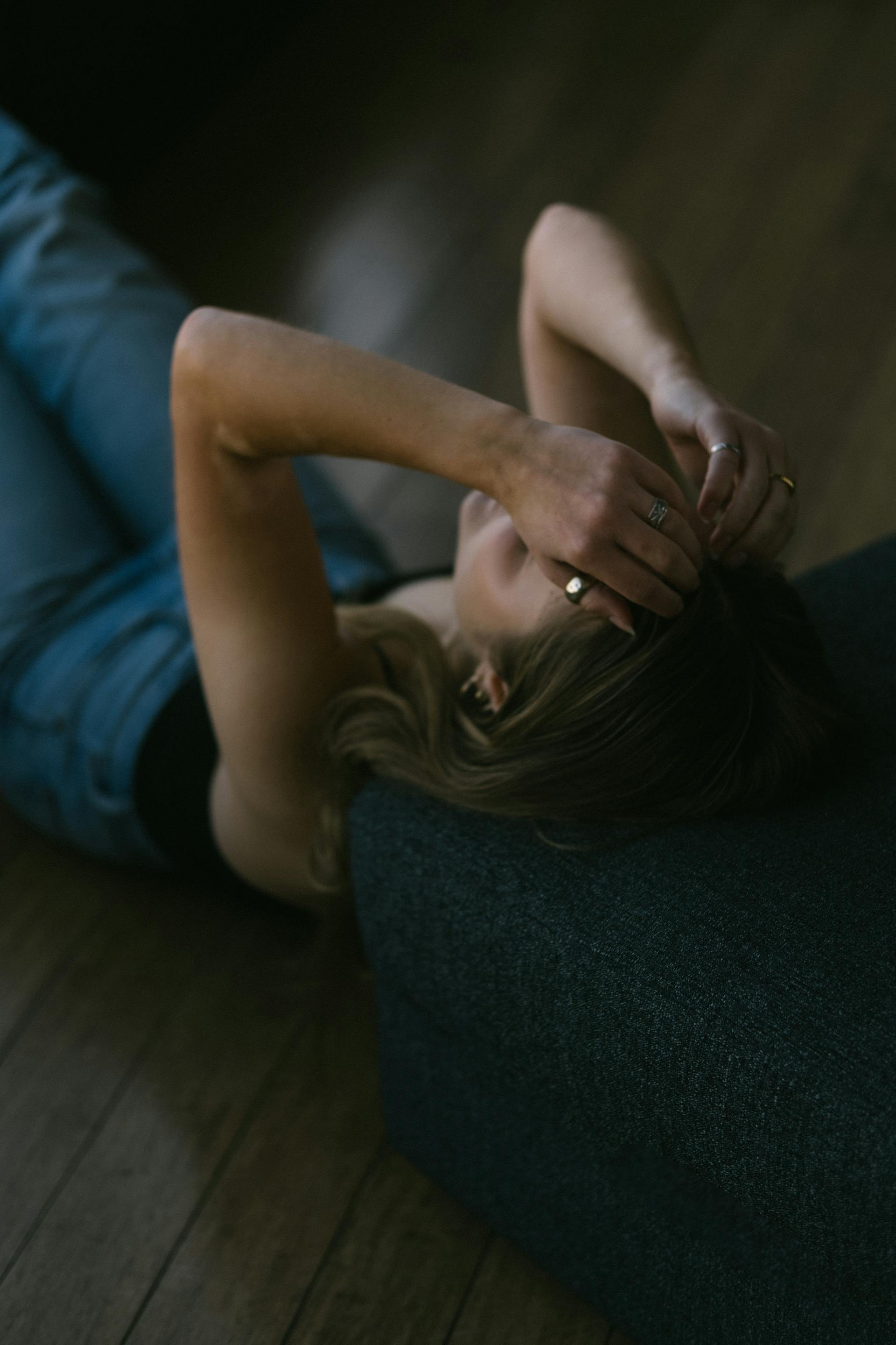 Una mujer tumbada en el suelo con las manos en la cabeza | Fuente: Pexels
