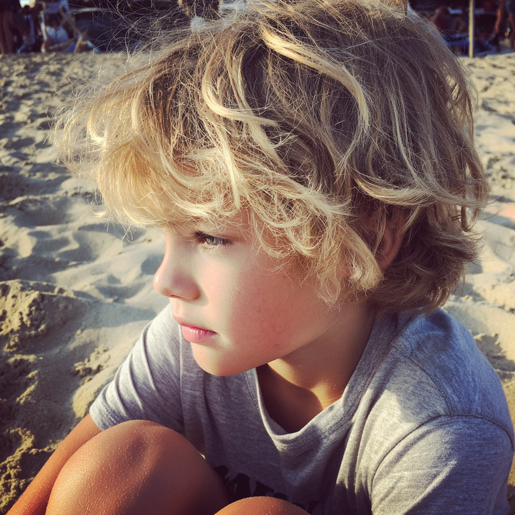 Un niño sentado en la playa | Fuente: Midjourney