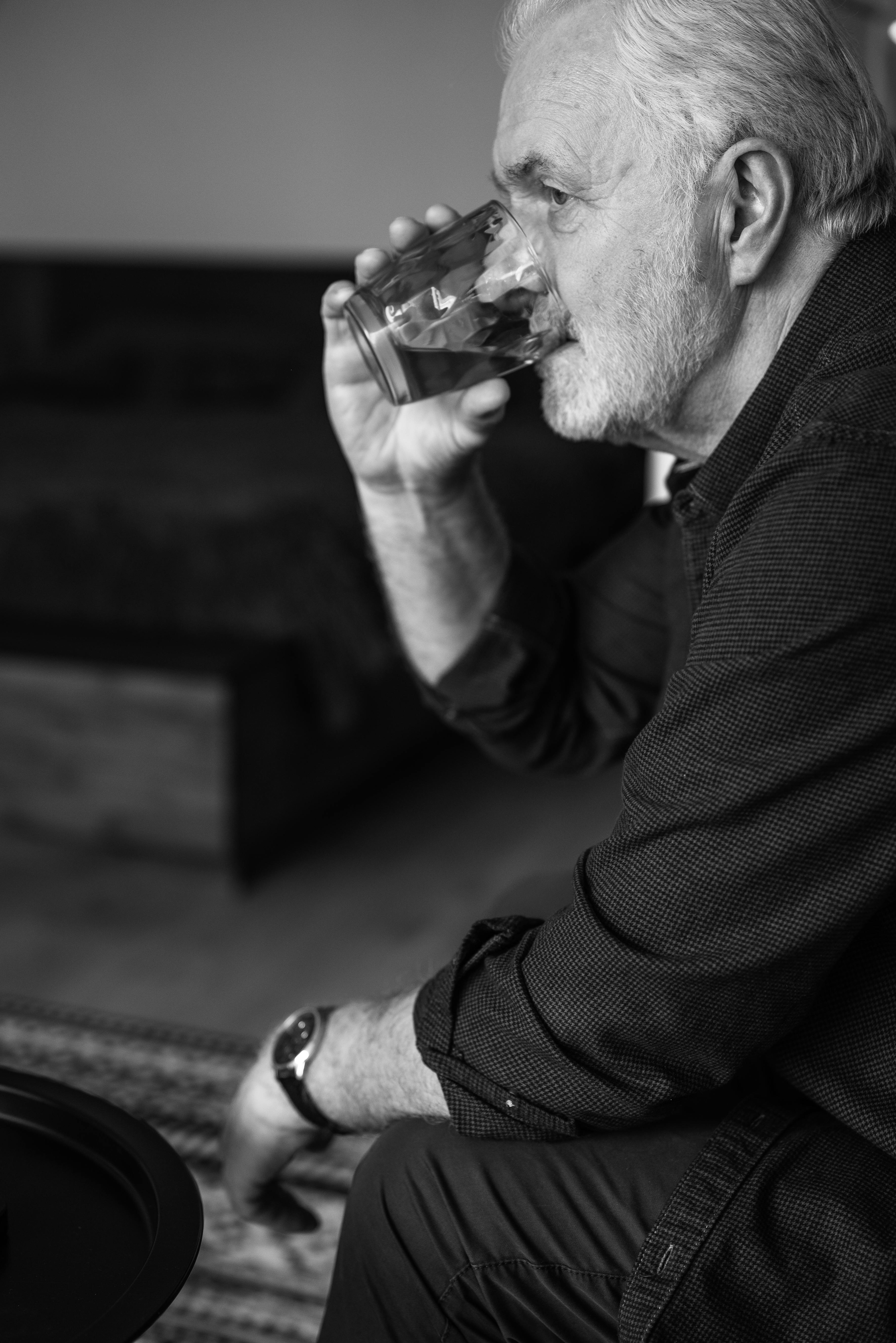 Hombre sentado en un sofá bebiendo agua | Fuente: Pexels