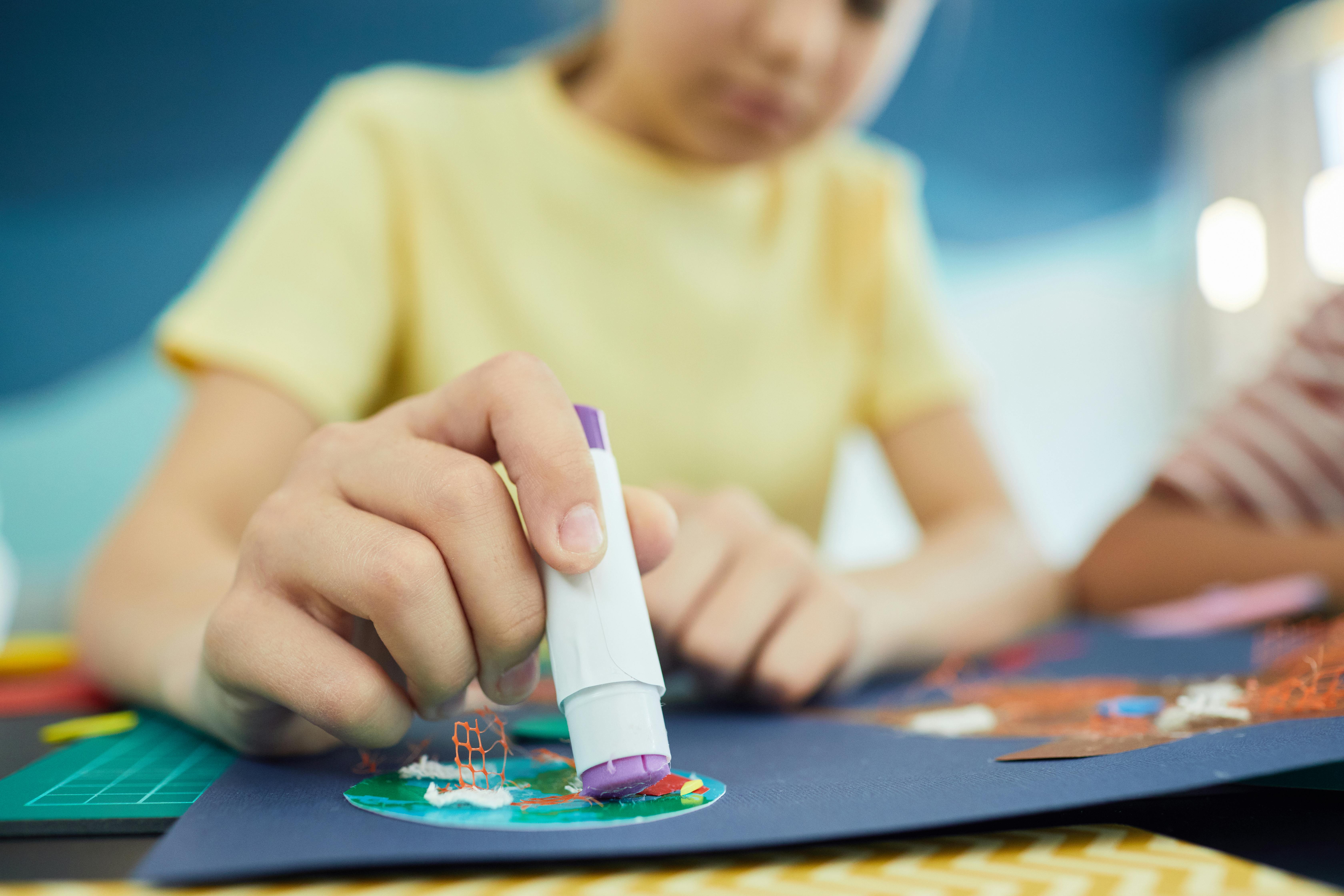 Un niño usando una barra de pegamento | Fuente: Pexels