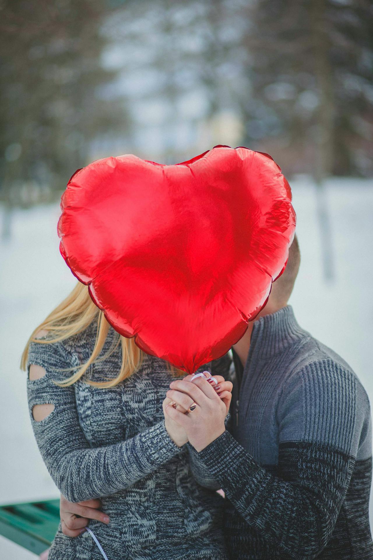 Una pareja romántica sujetando un globo rojo en forma de corazón | Fuente: Pexels