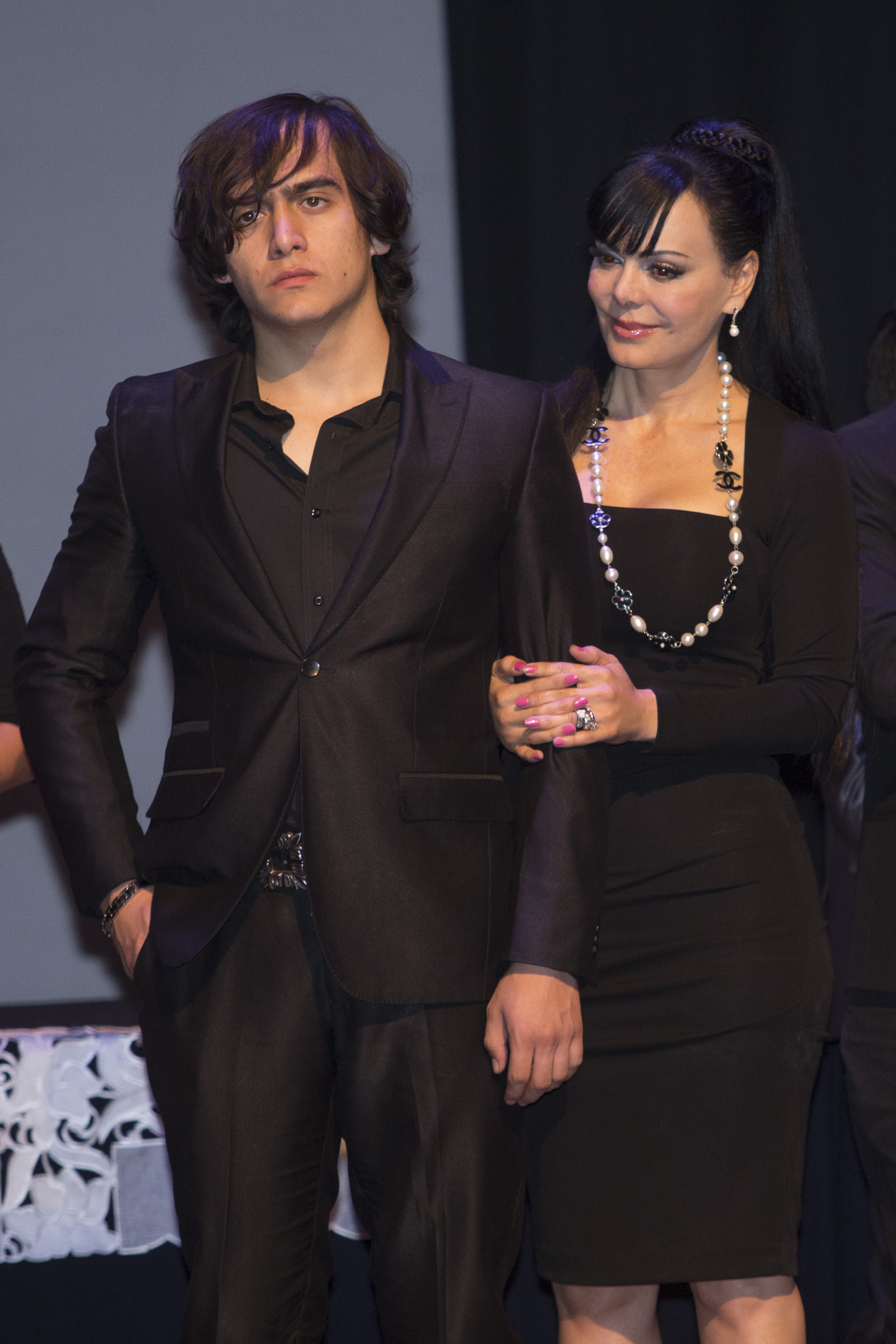 Maribel Guardia toma del brazo a Julián Figueroa durante el homenaje al cuerpo presente de su padre Joan Sebastian en la SACM el 16 de julio de 2015 en la Ciudad de México. | Fuente: Getty Images.