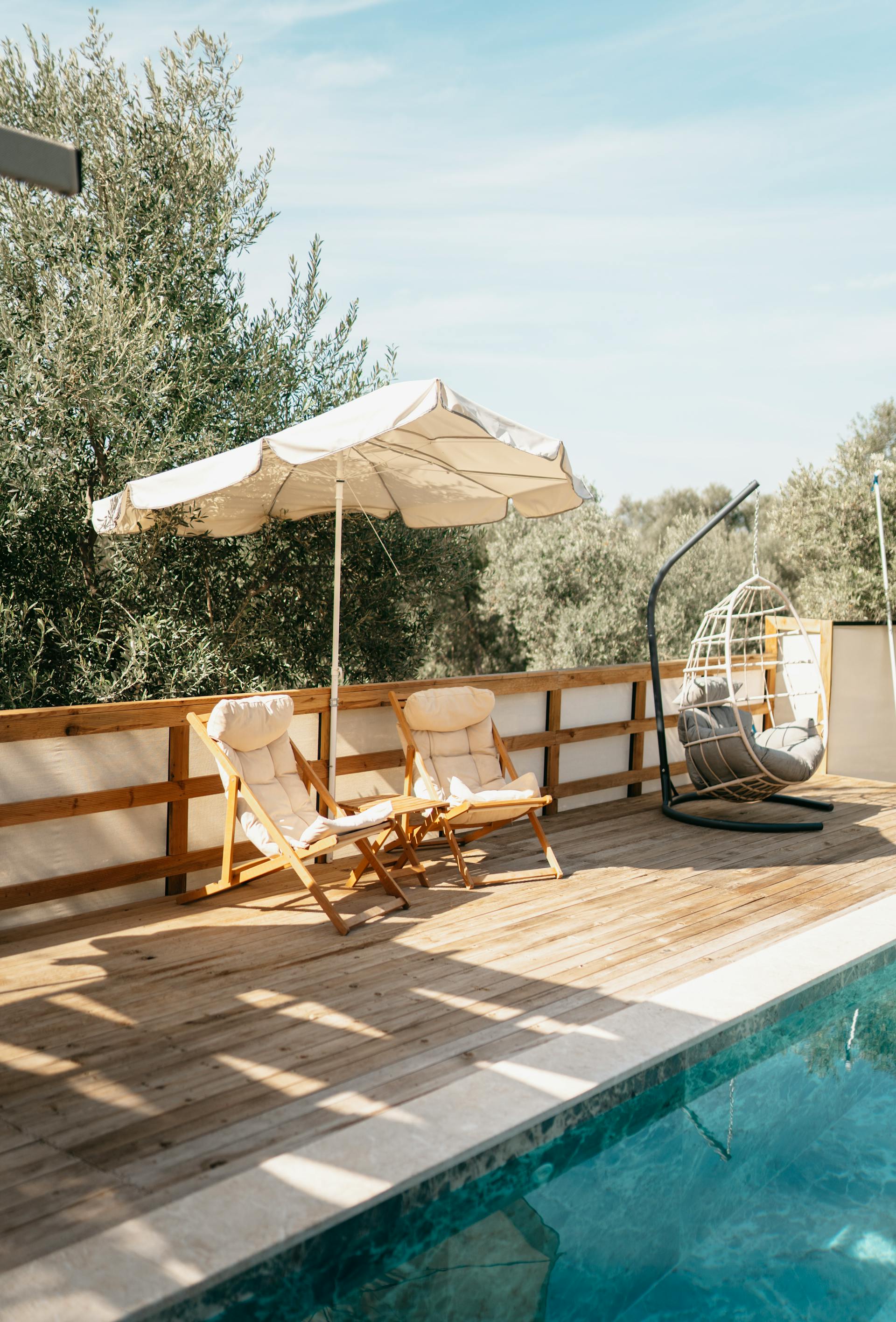 Una sombrilla y tumbonas colocadas cerca de una piscina | Fuente: Pexels