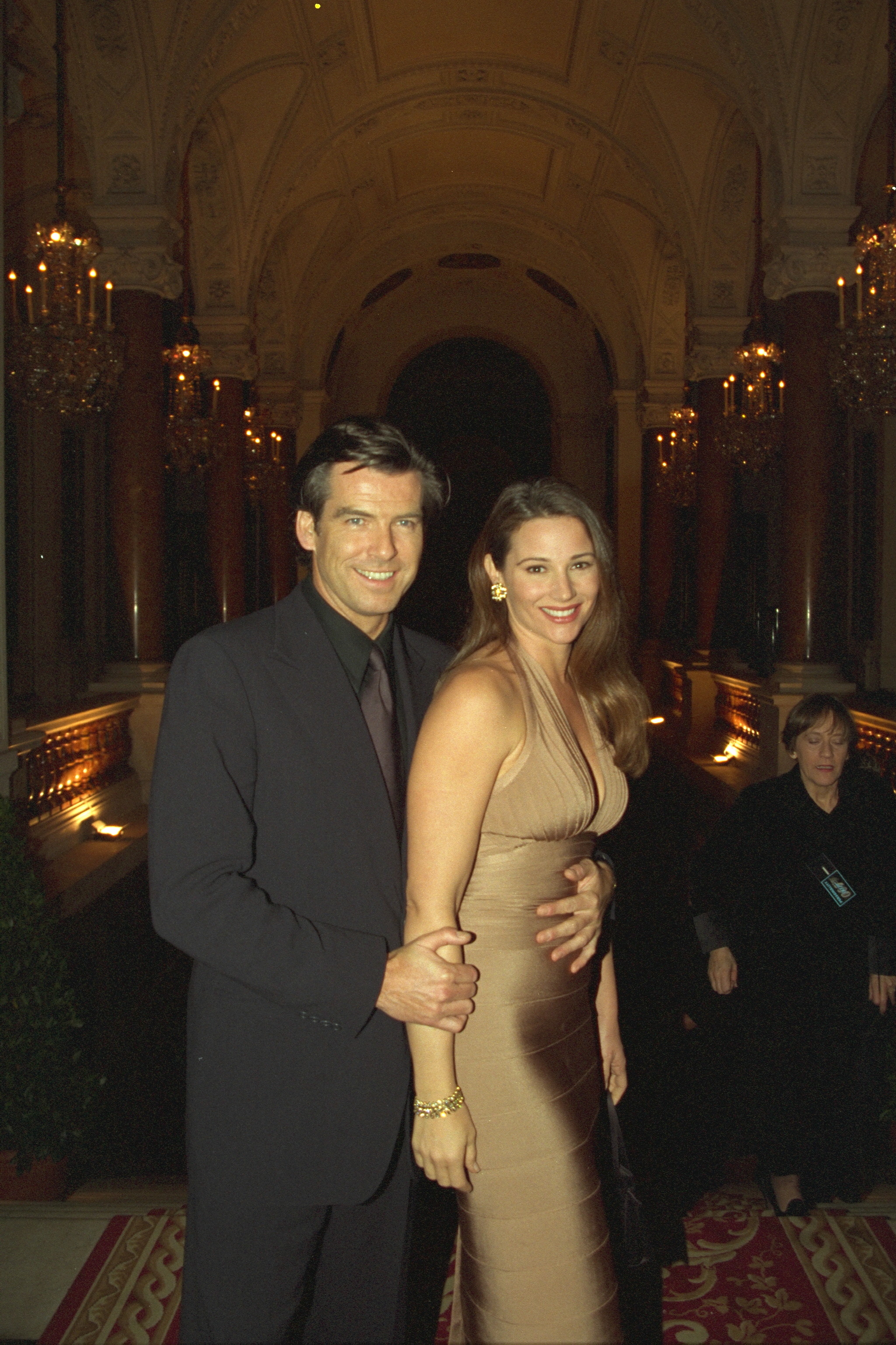 Keely Shaye Smith, embarazada, posa junto a Pierce Brosnan mientras él le pone cariñosamente una mano sobre su barriguita, solo unos meses antes de que naciera su hijo. | Fuente: Getty Images.