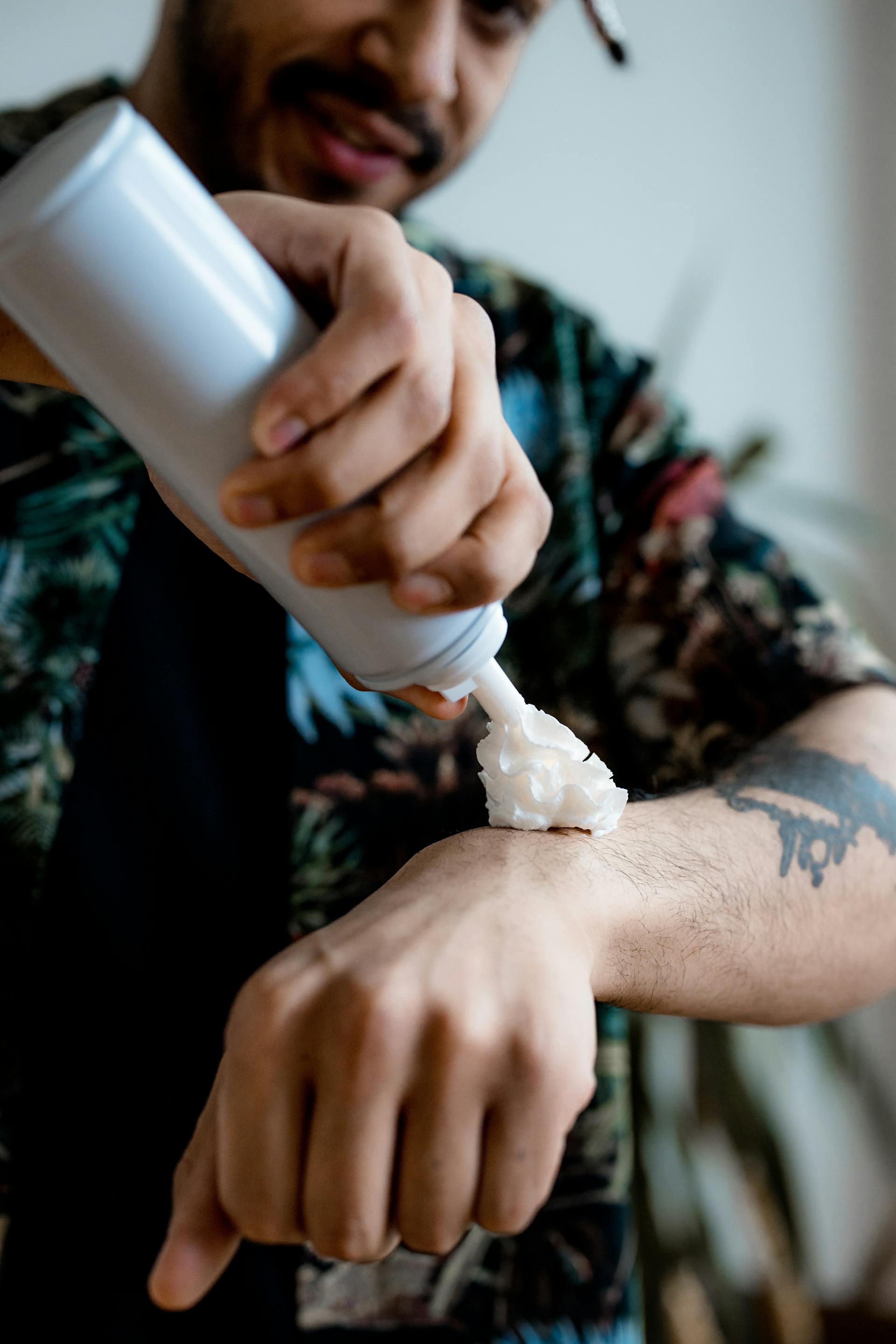 Un hombre rociándose nata montada en el brazo | Fuente: Pexels