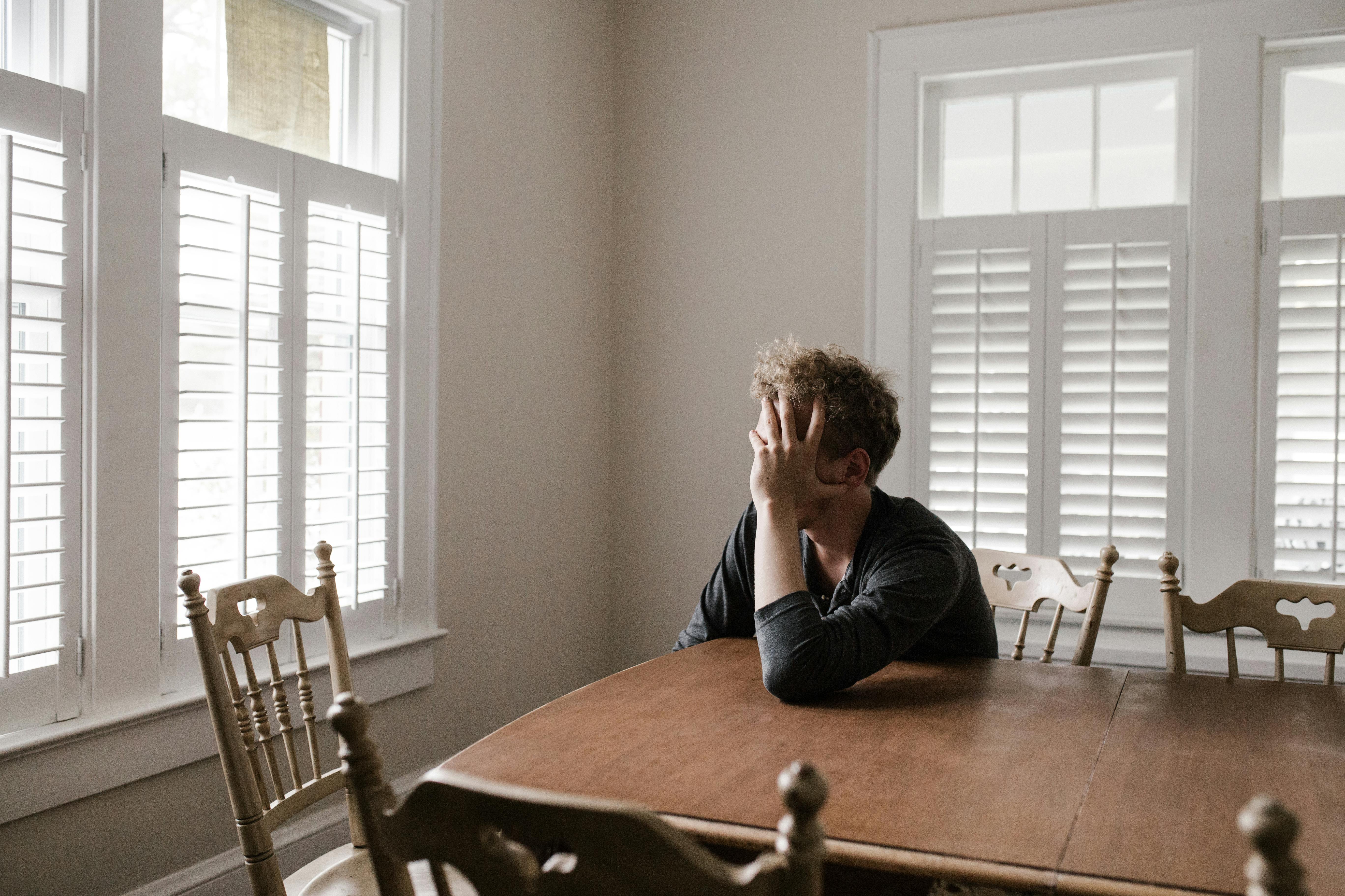 Un hombre disgustado sentado en una mesa | Fuente: Pexels