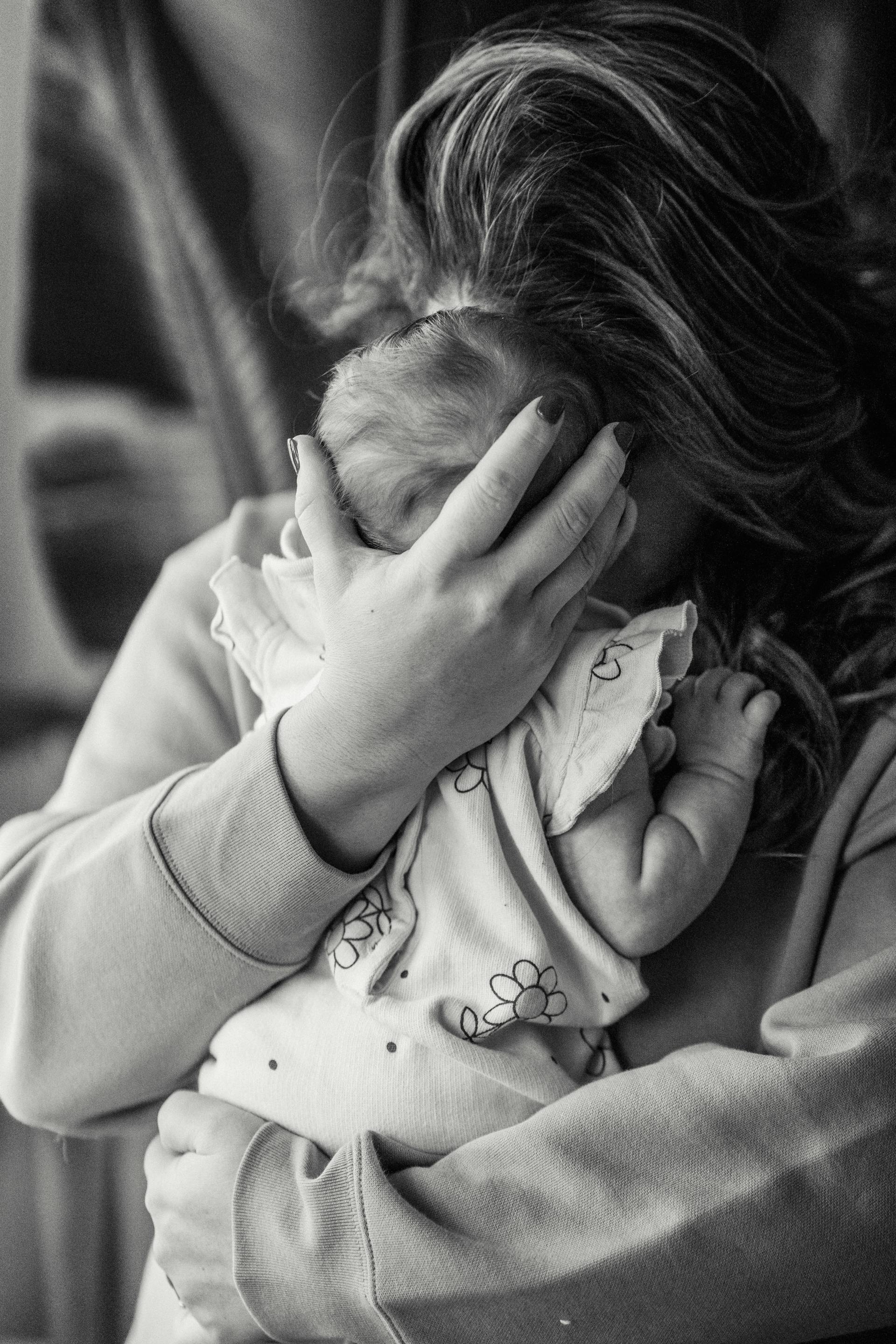 Foto en escala de grises de una mujer abrazando a su bebé | Fuente: Pexels