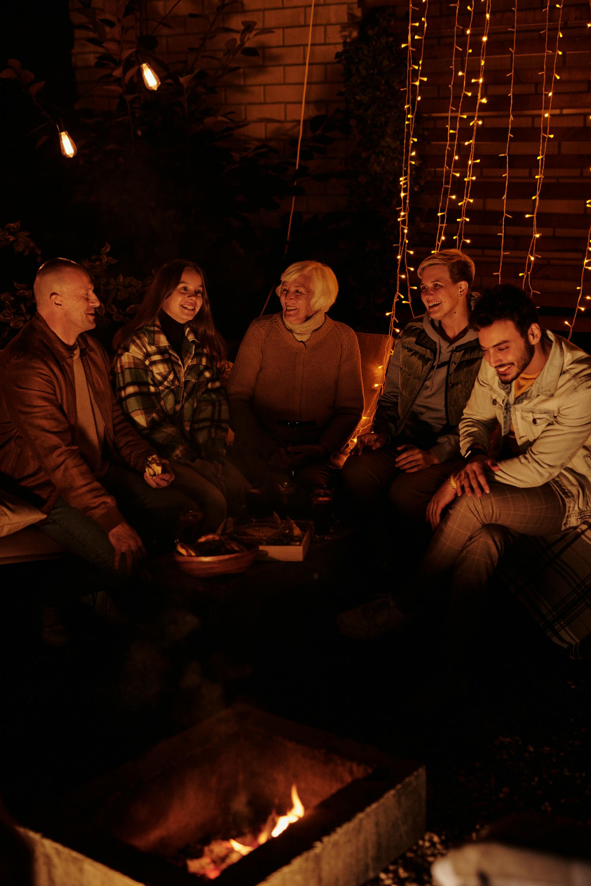 Una familia reunida alrededor de una hoguera por la noche | Fuente: Pexels